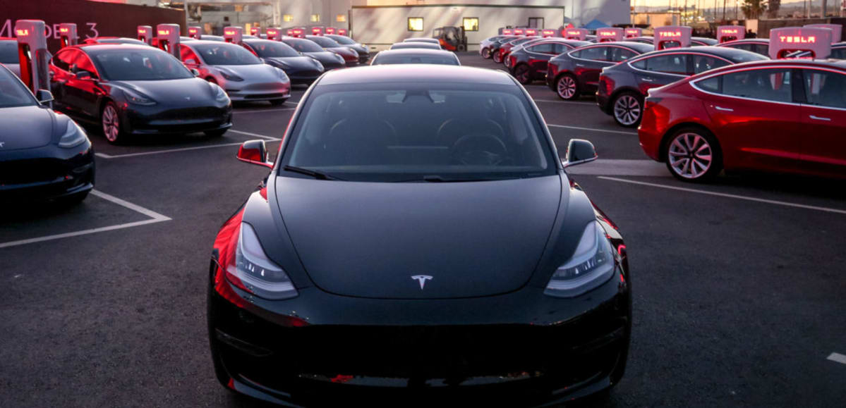 A bunch of Tesla Model 3 vehicles, lined up ready for delivery.