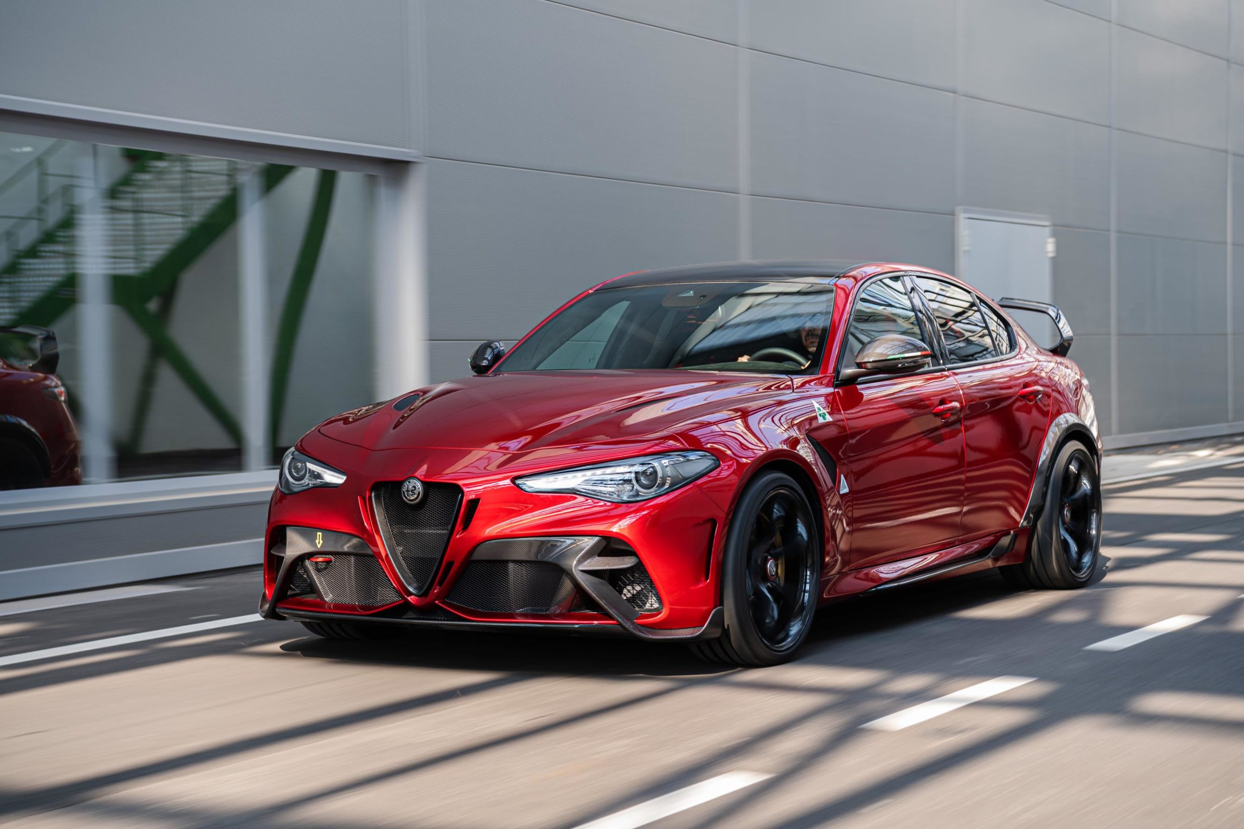 front of a red Alfa Romeo Giulia GTAm