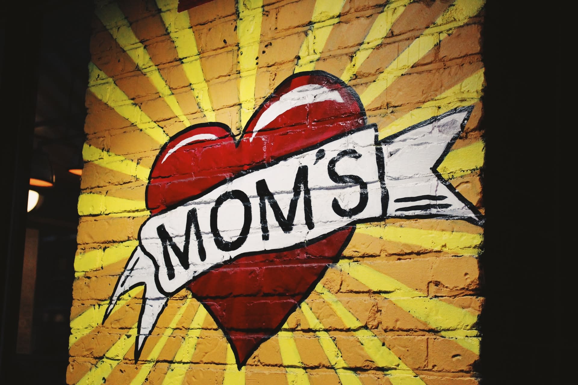 wall-art with "MOM'S" written across a heart with a yellow background.