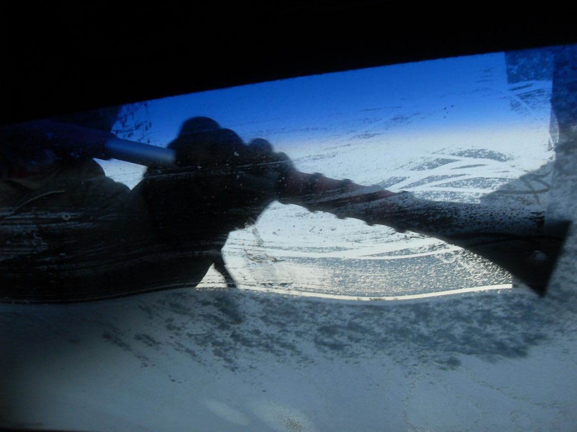 image taken from inside a car looking out through the windshield where someone has scraped off the ice.
