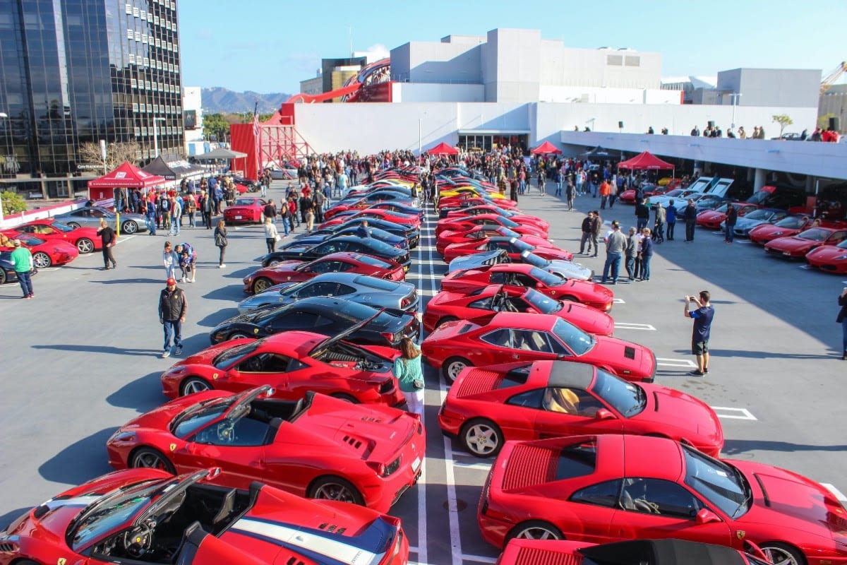 a massive collection of Ferraris - mainly red - in the parking lot of The Petersen.