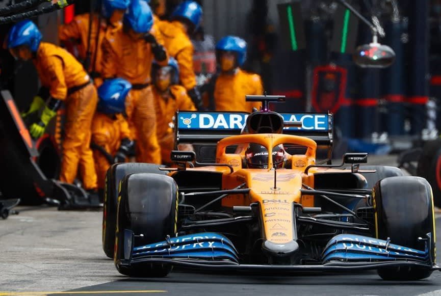 orange race car coming out from a pit-stop