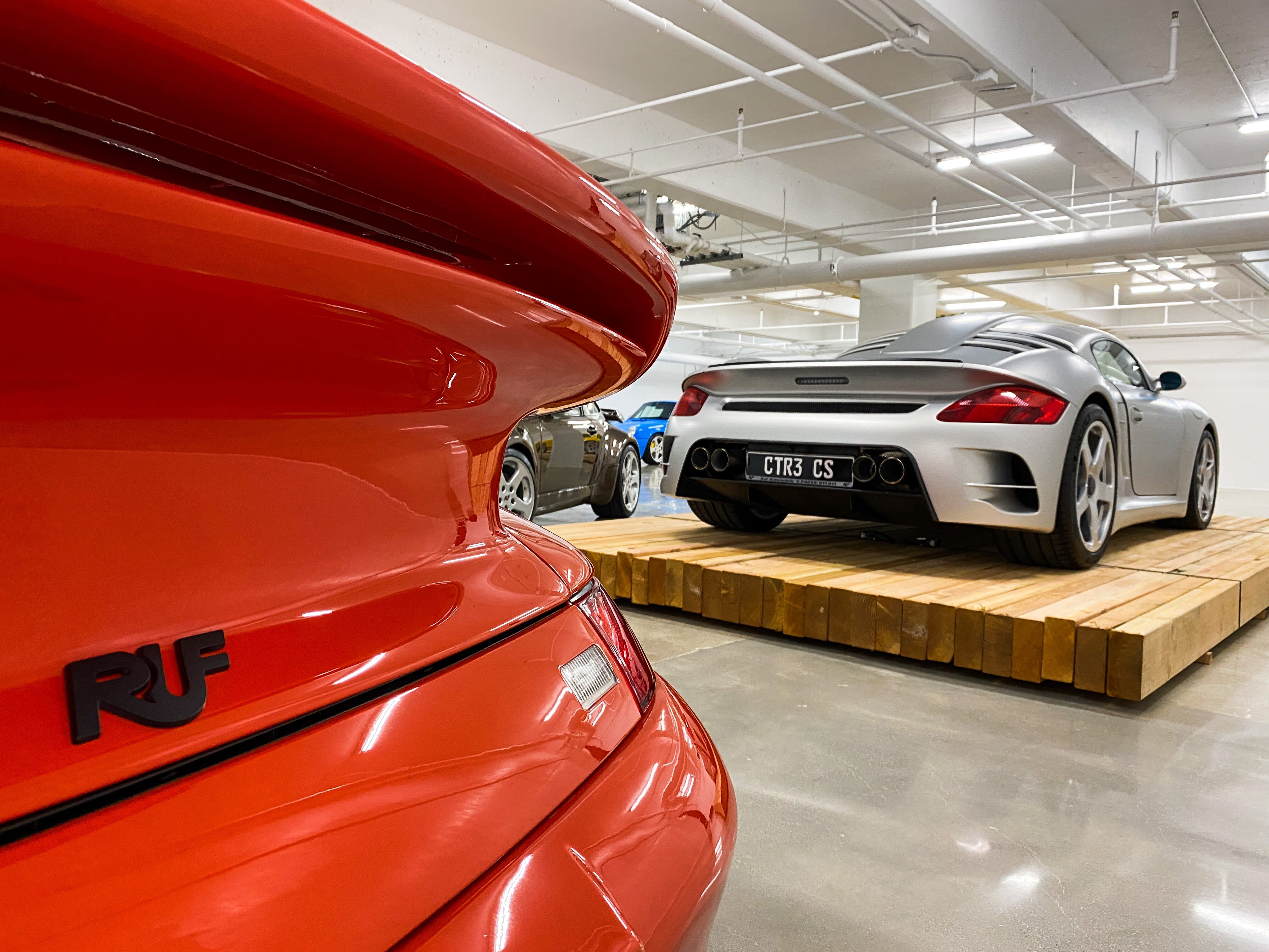 a red RUF Porsche on the exhibition floor of The Petersen Museum in Los Angeles, with a silver RUF in the background.