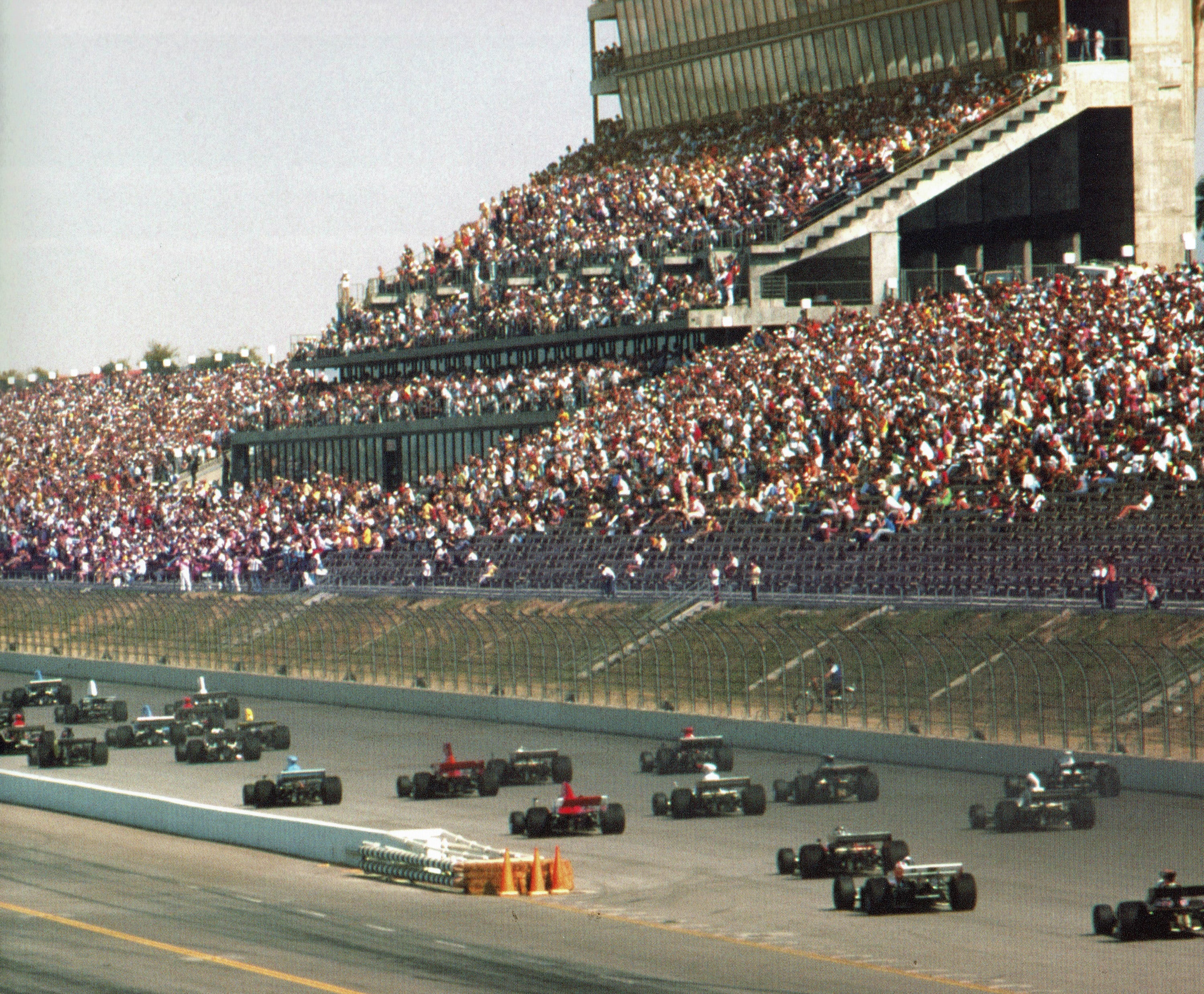 formula 500 racers speeding down the track with spectators in the stands in the background