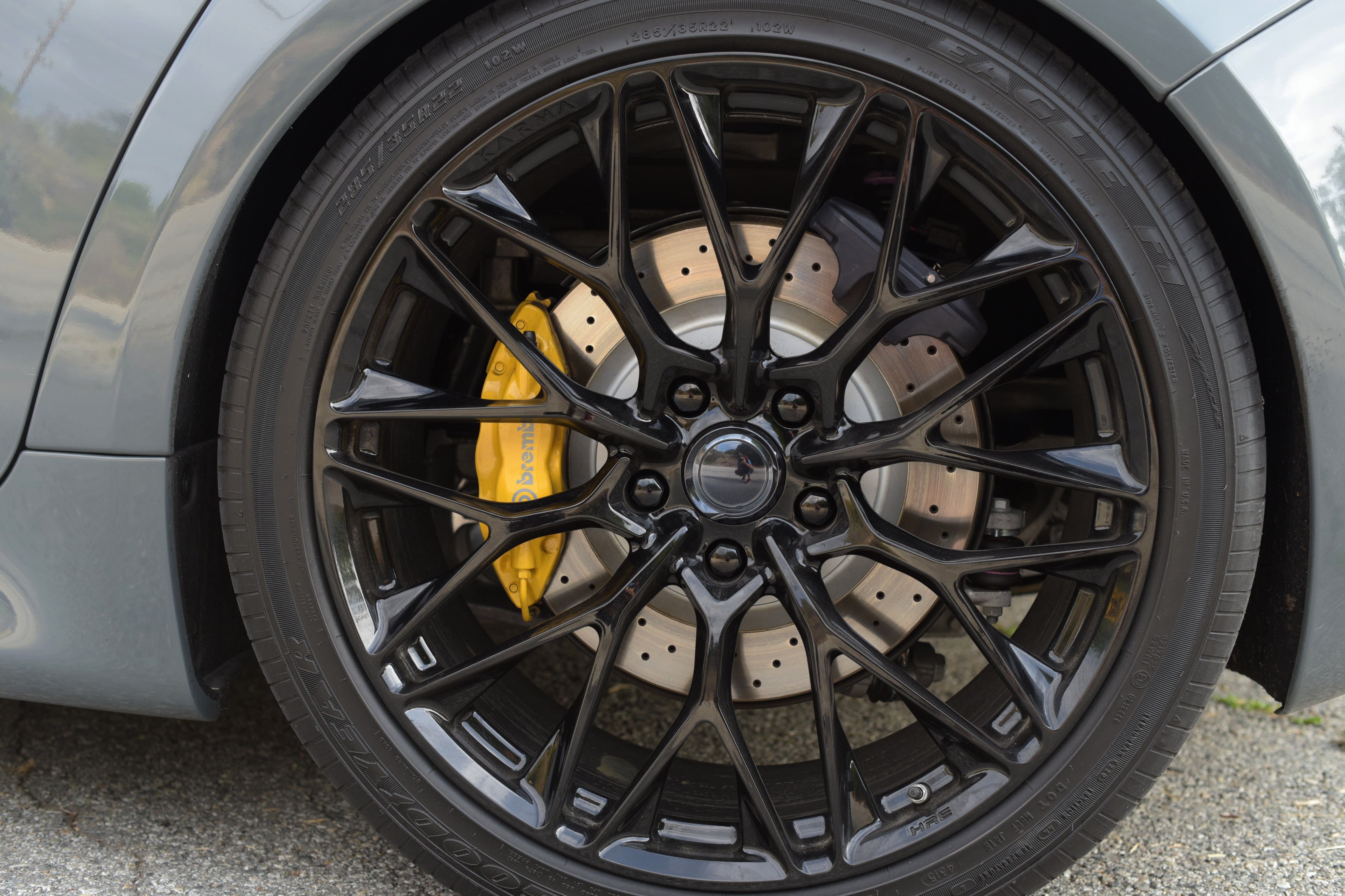 close-up image of the wheel of a Karma GS-6 with yellow brakes behind black rims
