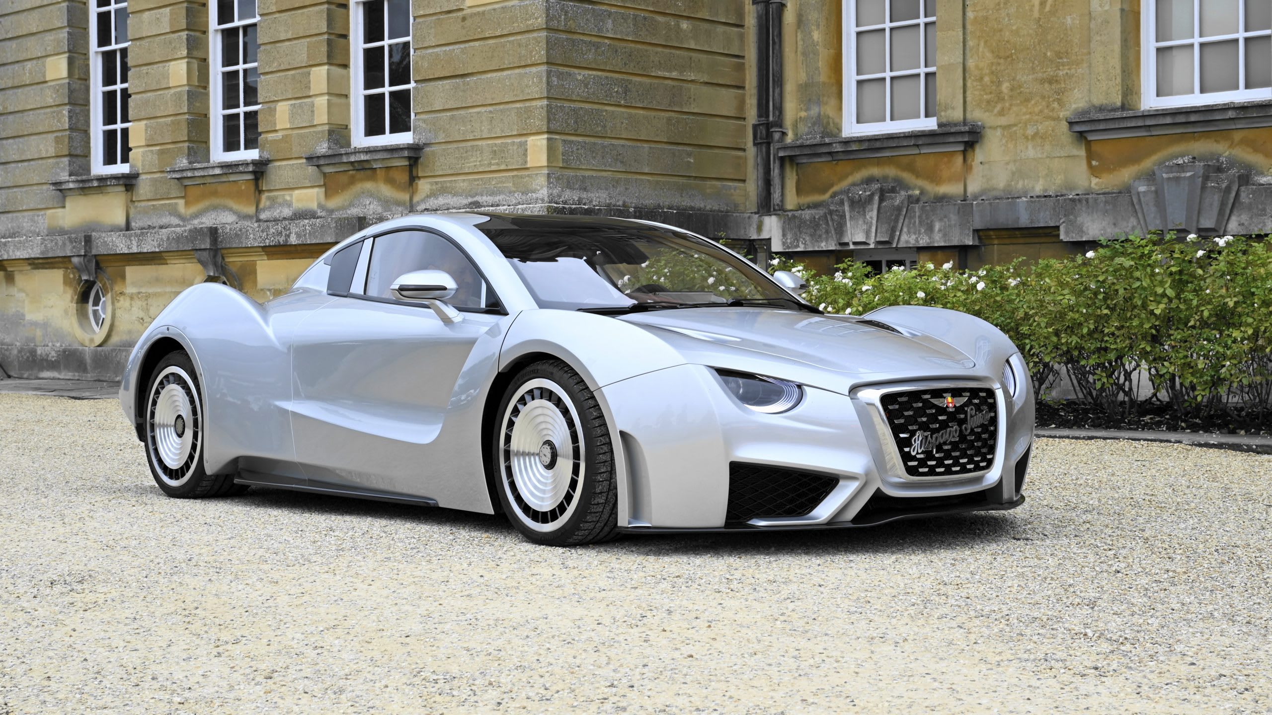 a bright silver Hispano Suiza Carmen on the gravel with the old bricks of the castle in the background