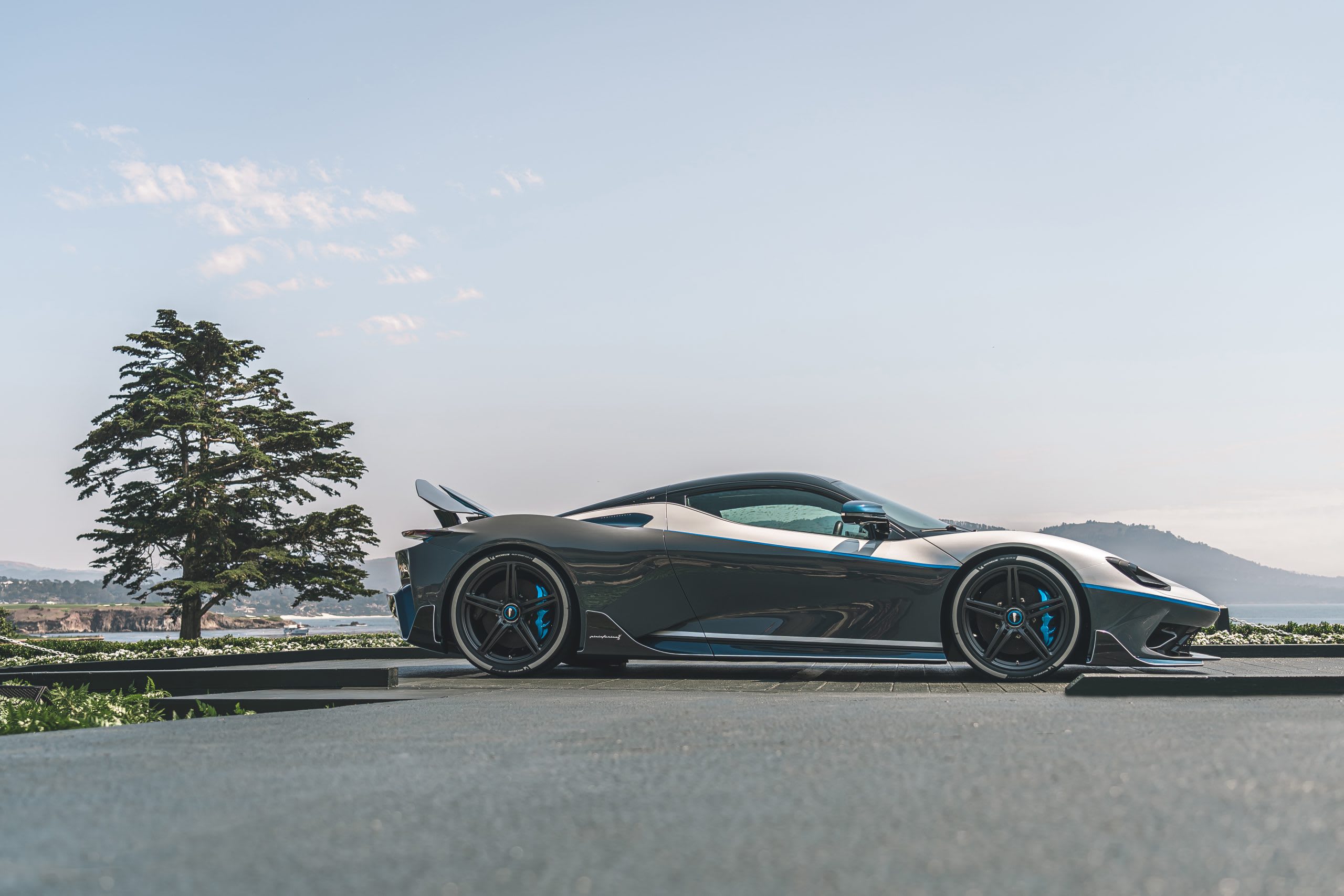 A Battista Anniversario from Automobilia Pininfarina in silver grey with blue brakes and blue styling lines.