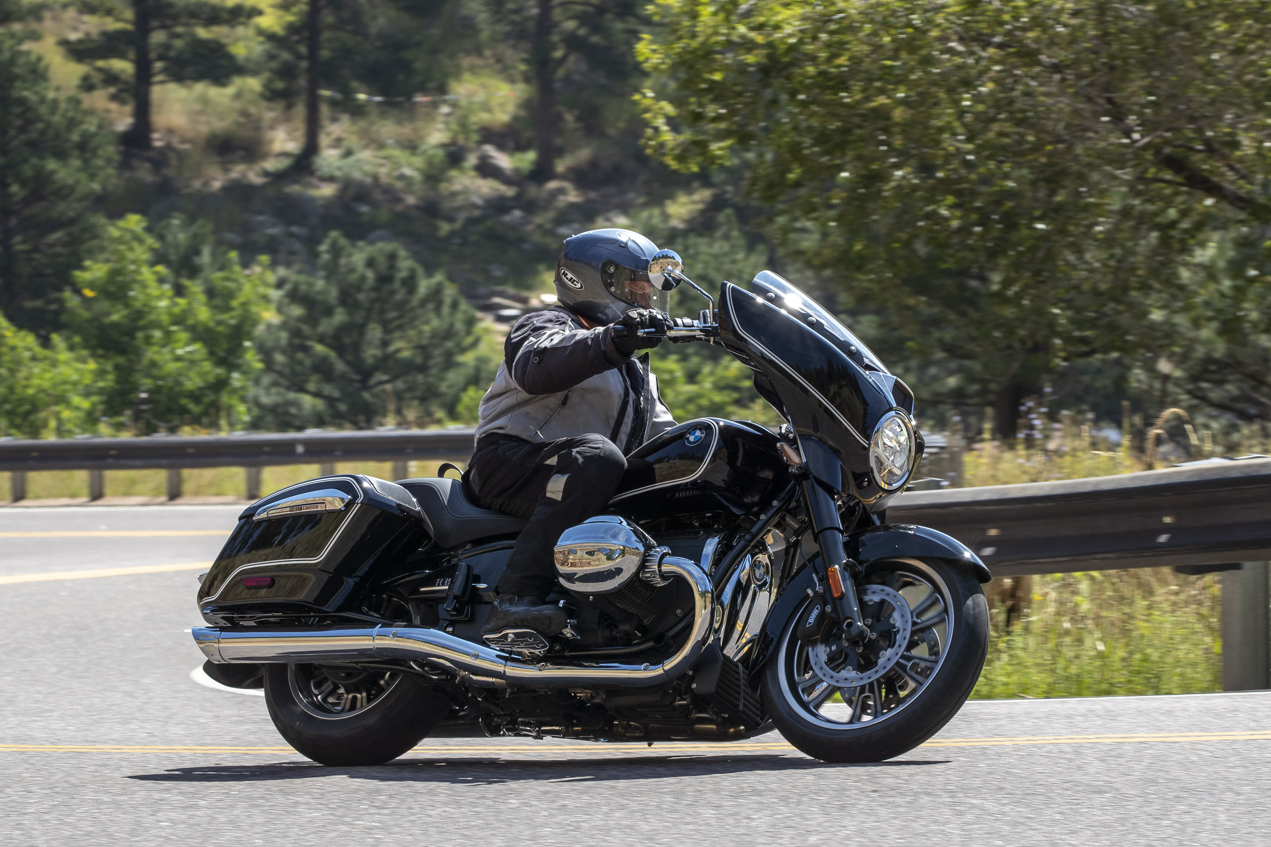 A BMW R 18 B taking a corner on a highway through the forests of Colorado.