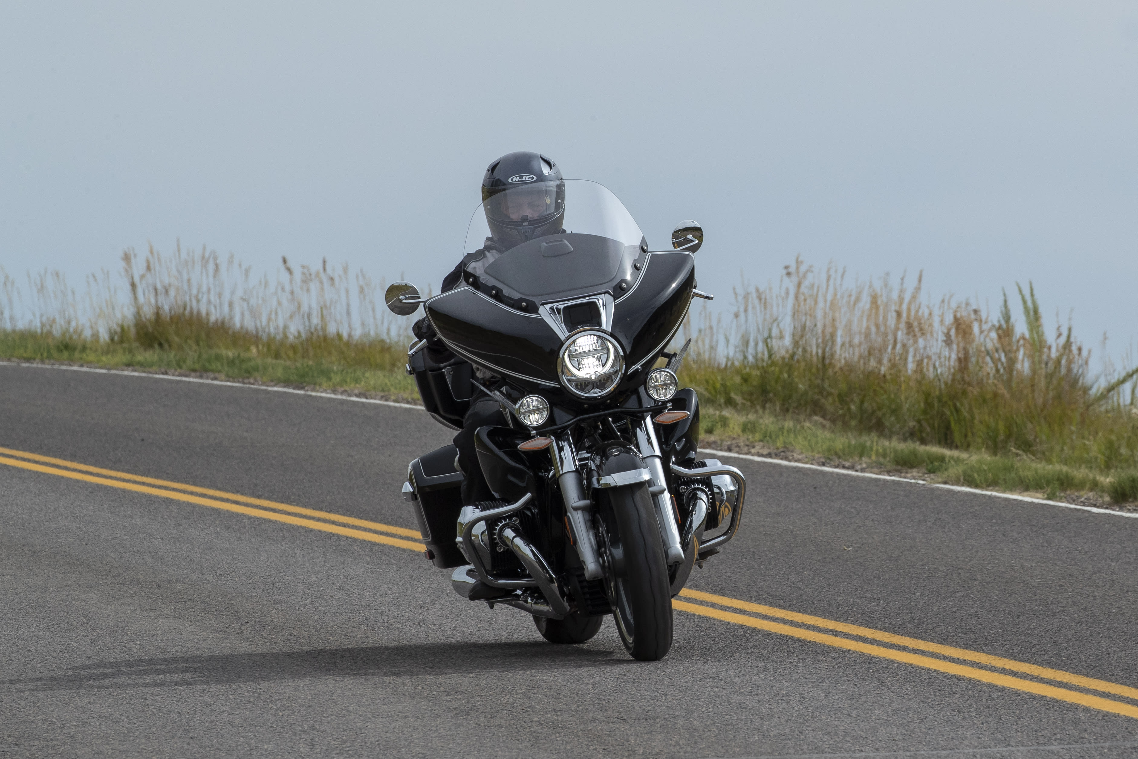 A BMW R 18 Transcontinental driving towards the camera on a road that looks to run along a cliff with a view.