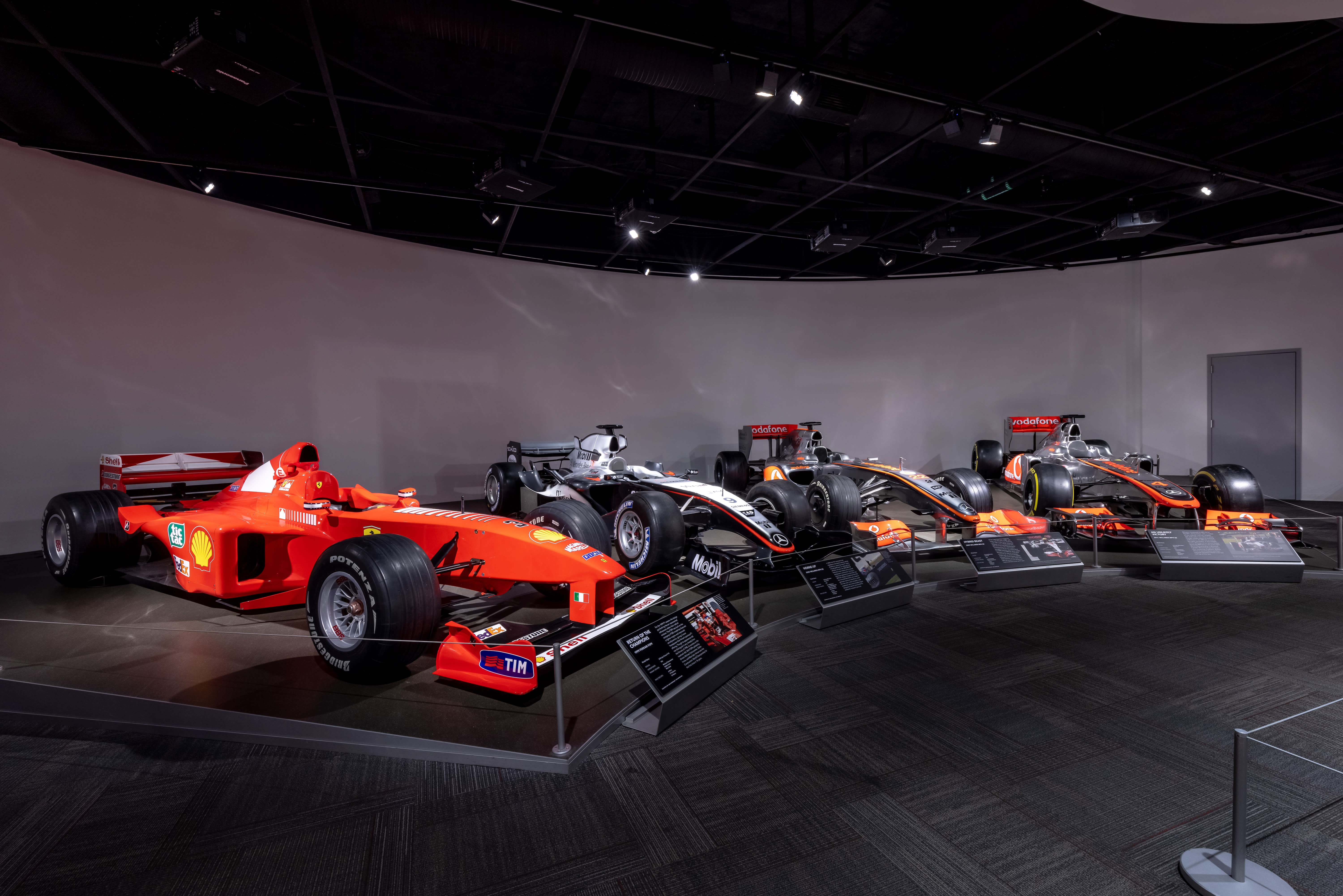 an overview of four cars at the Juan Gonzalez Formula 1 Collection at the Petersen Automotive Museum.