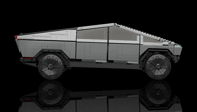 An image of the side of the Mattel Creations scale model of the Tesla Cybertruck. The truck is gray, with a black background.