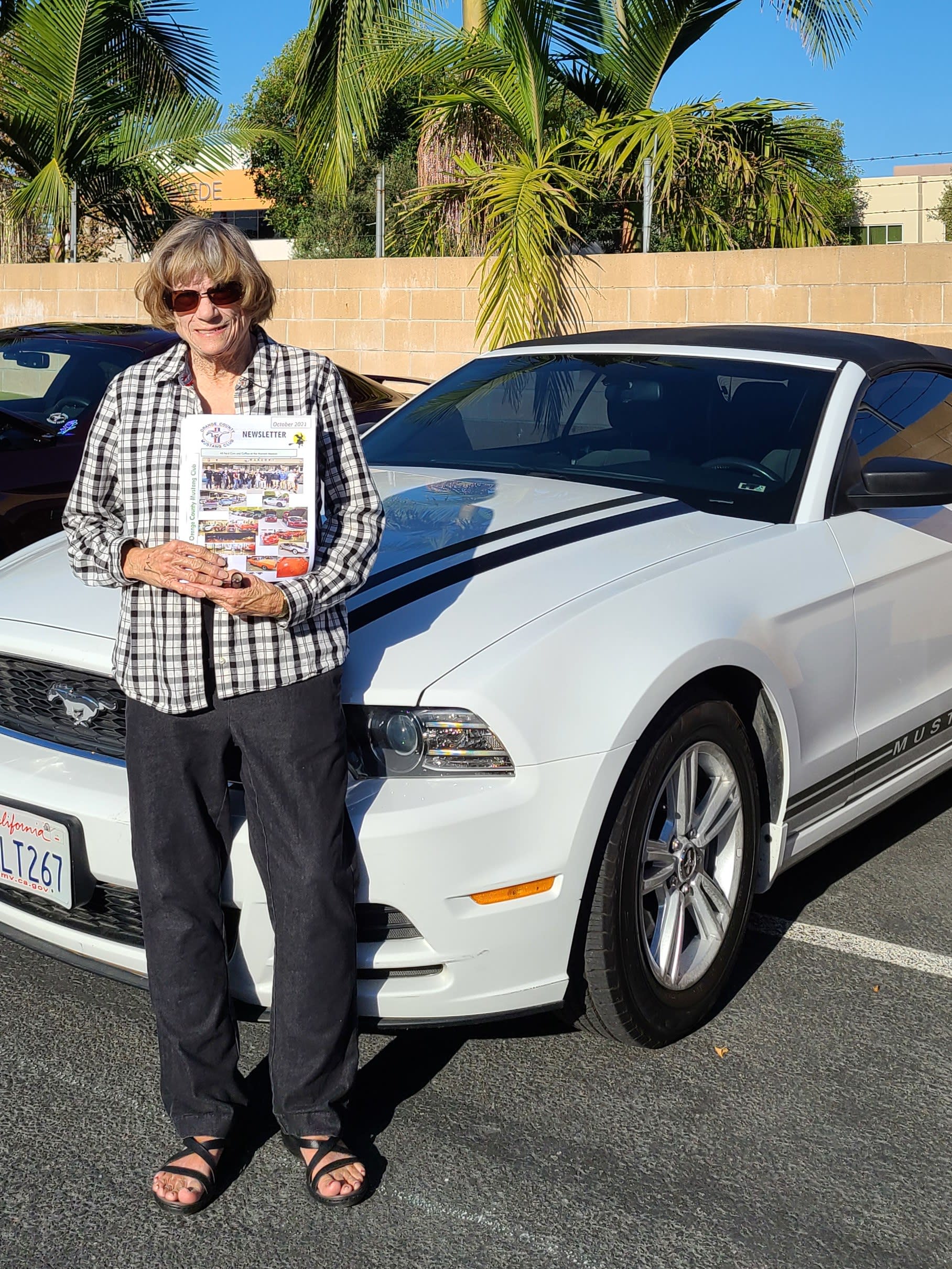 a white with black stripes 2014 Mustang with owner Diana in the foreground.