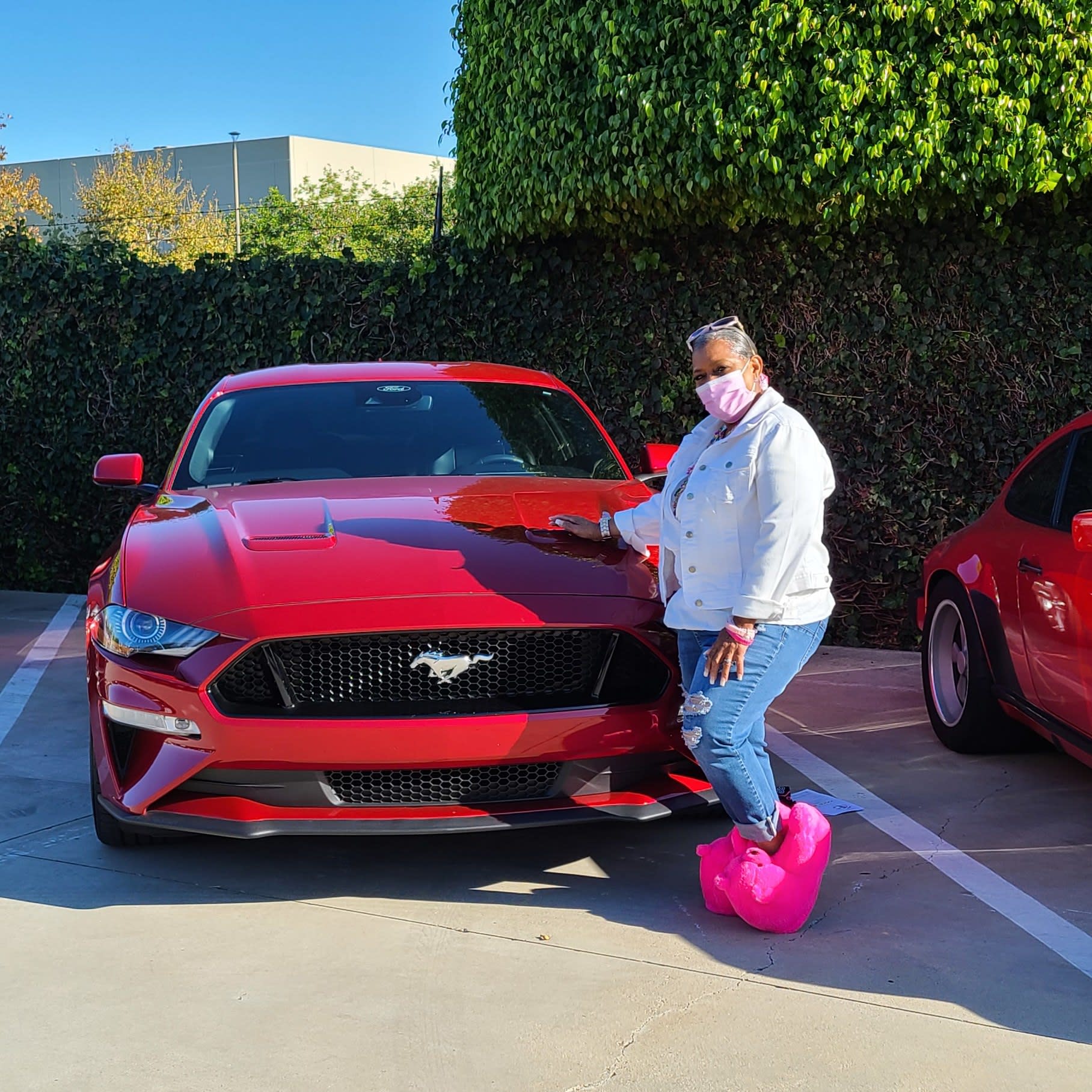 Tammy in pink fluffy shoes next to her 2021 red Mustang