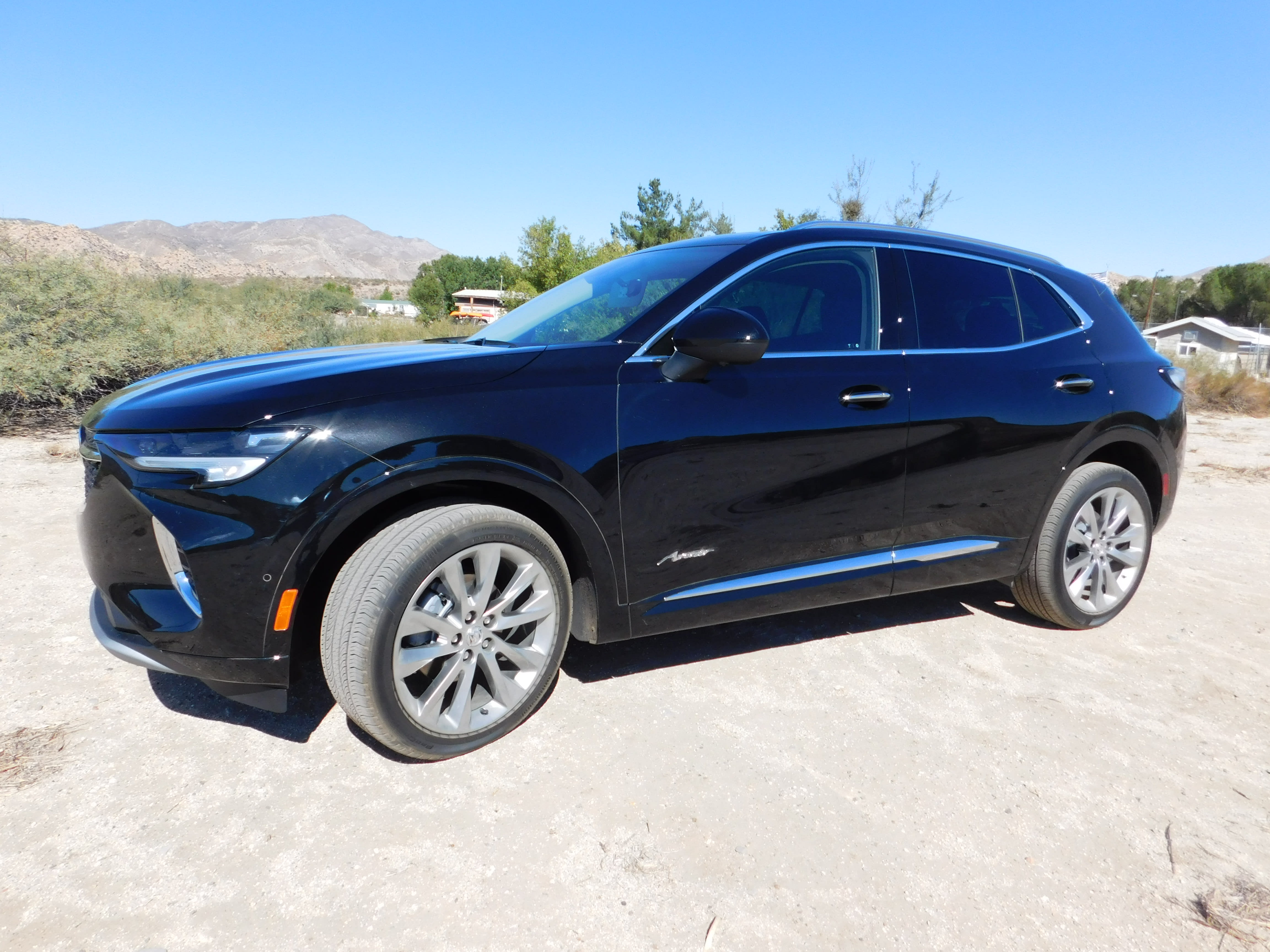 a dark colored 2022 Buick Envision Avenir, with the desert in the background.
