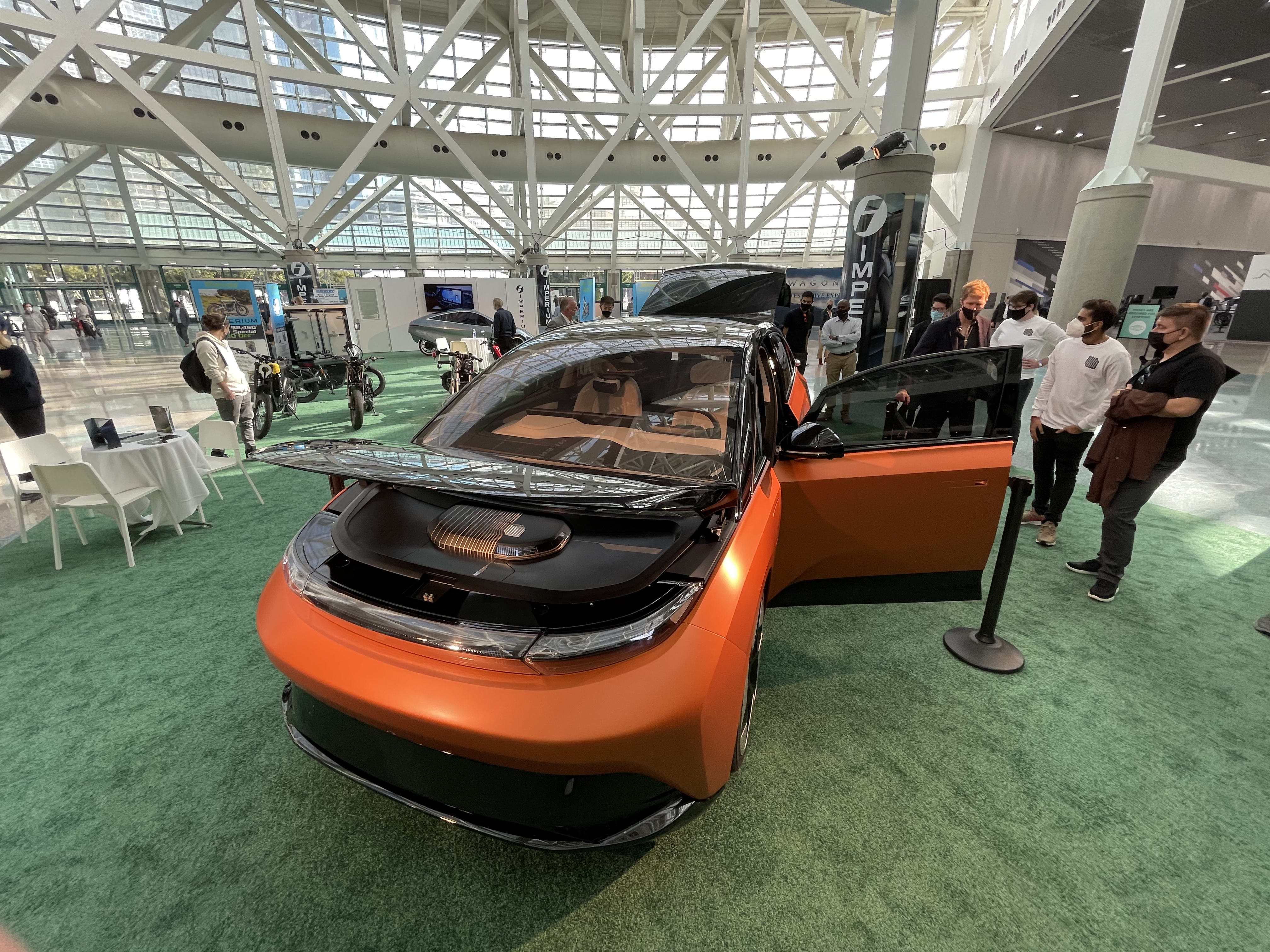 Indi One on display at the LA Auto Show with journalists around it taking pictures.
