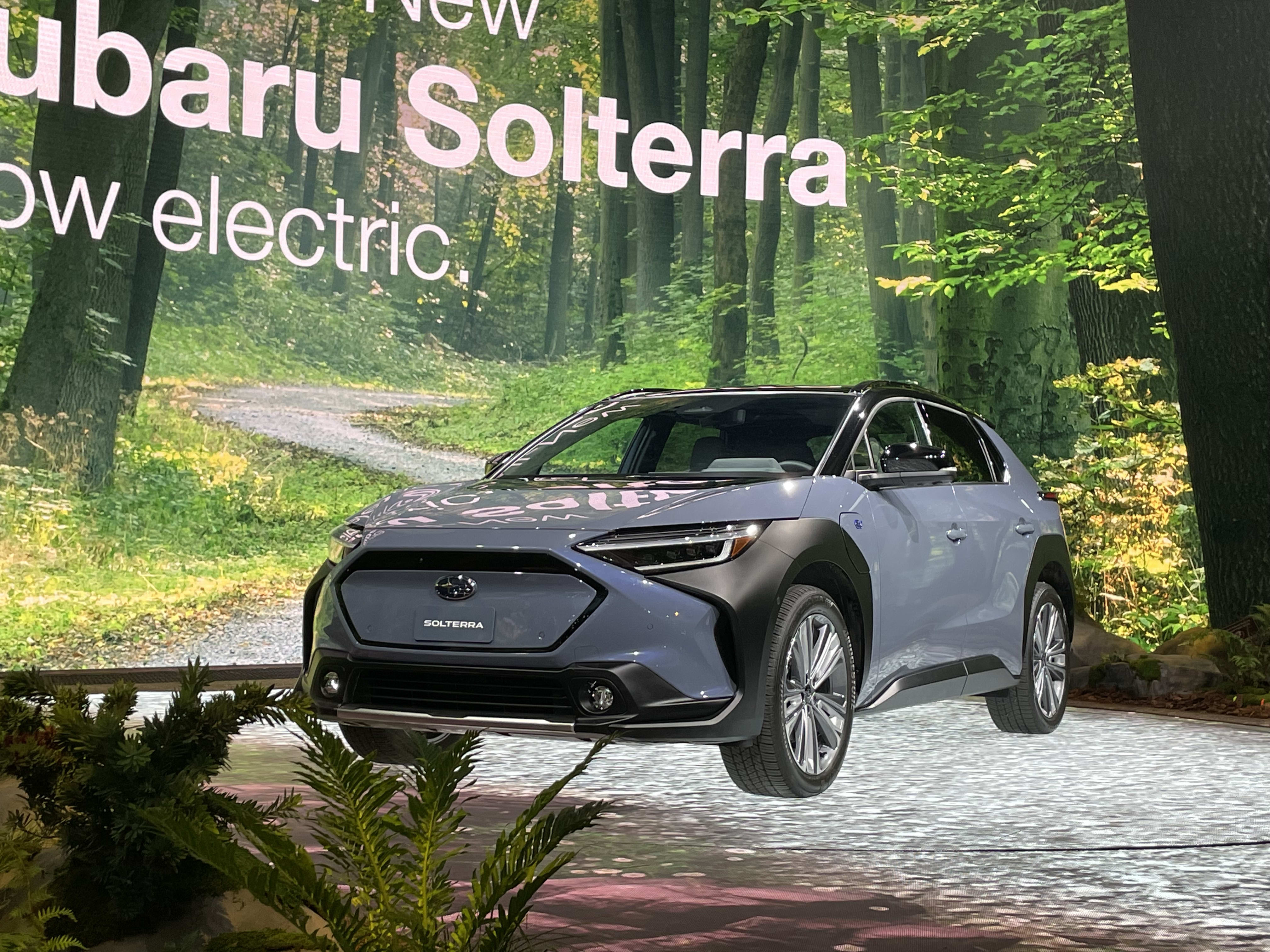 A Subaru Solterra on display at the 2021 Los Angeles Auto Show, with jungle-theme surroundings.
