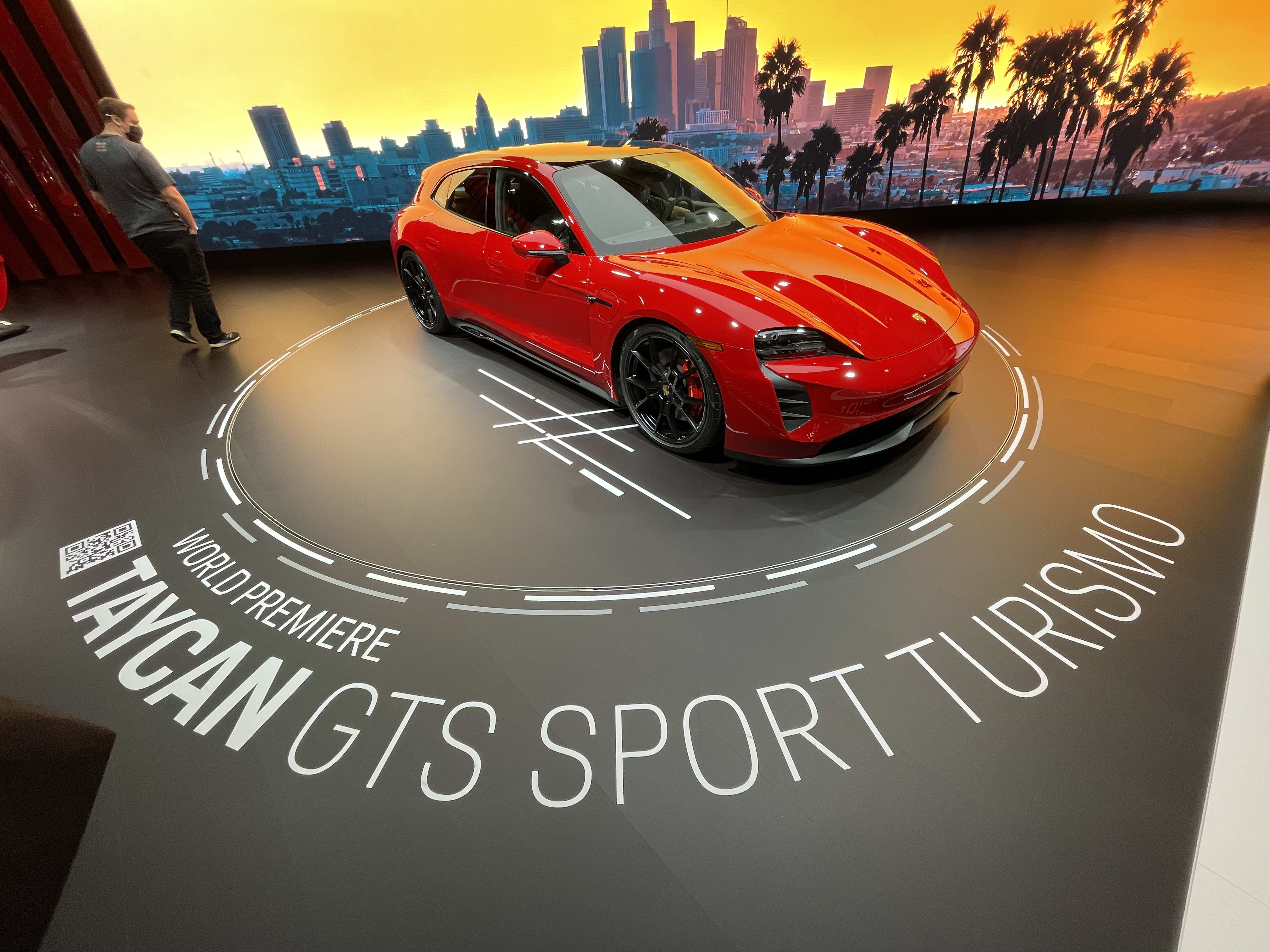 a bright red - almost orange - Porsche Taycan GTS Sport Turismo on display at the LA Auto Show 2021.