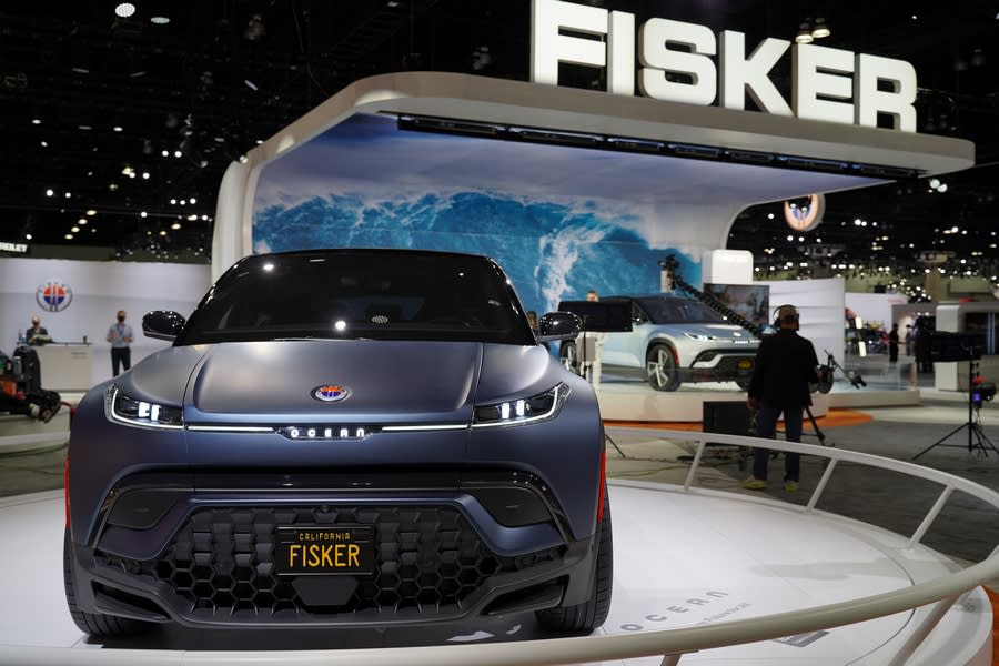the new Fisker Ocean revealed at the LA Auto Show, standing on display with journalists surrounding it.