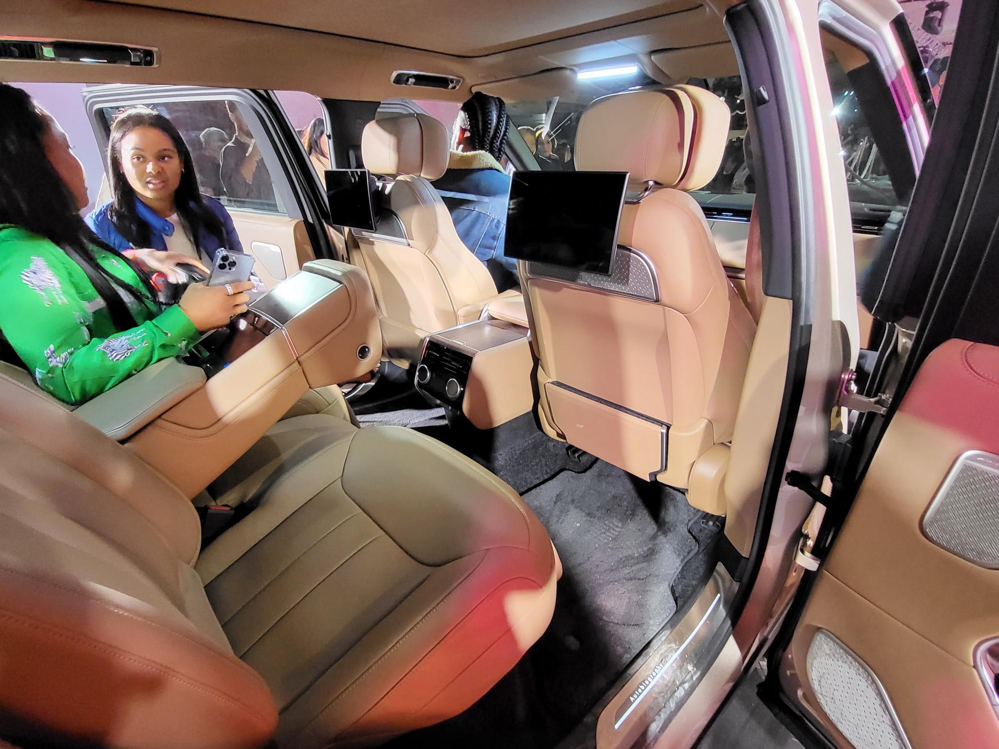 interior of the new Range Rover, with light brown leather seats, and two other visitors looking in from the other side door.
