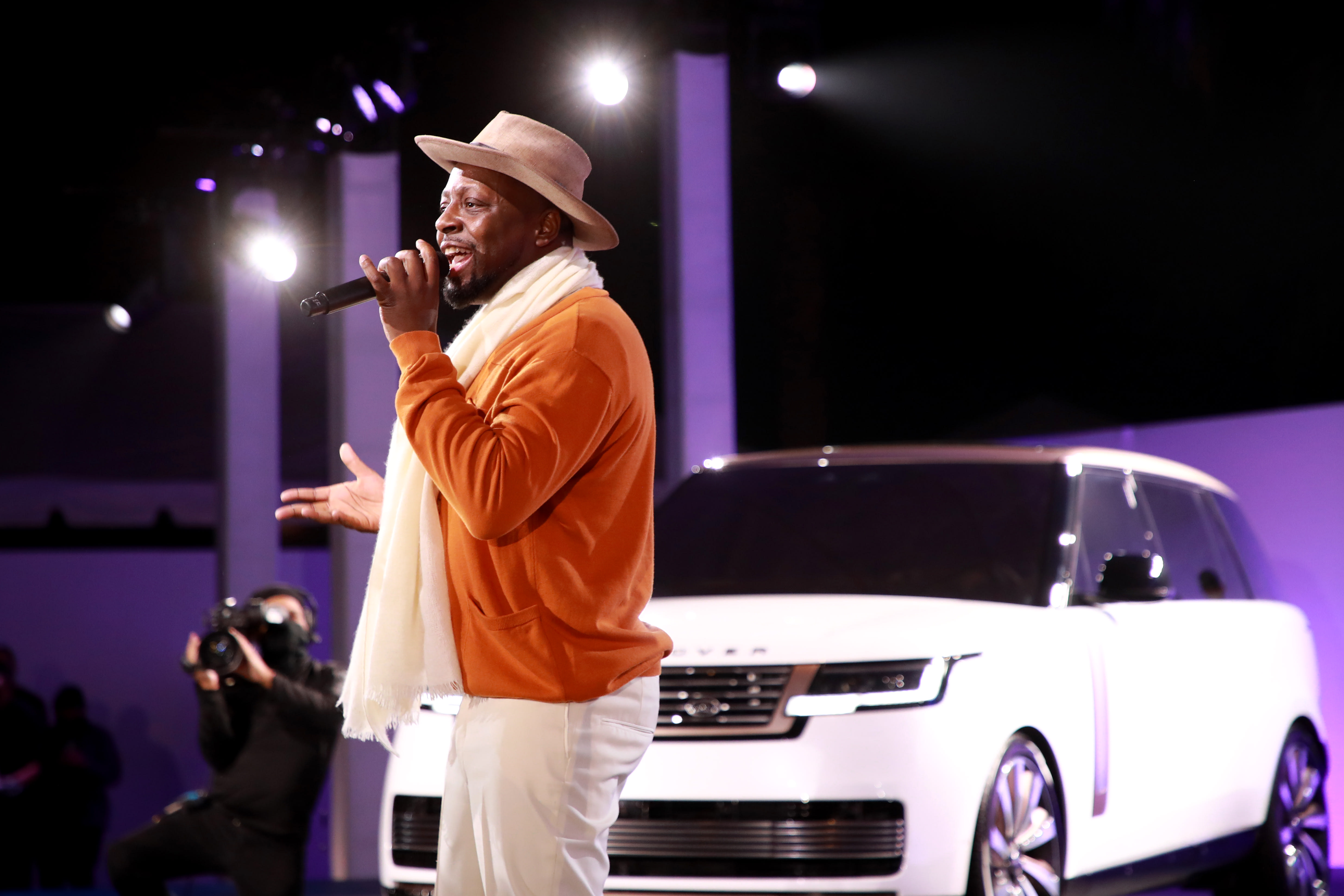 Wyclef Jean performing right next to a new white Range Rover.