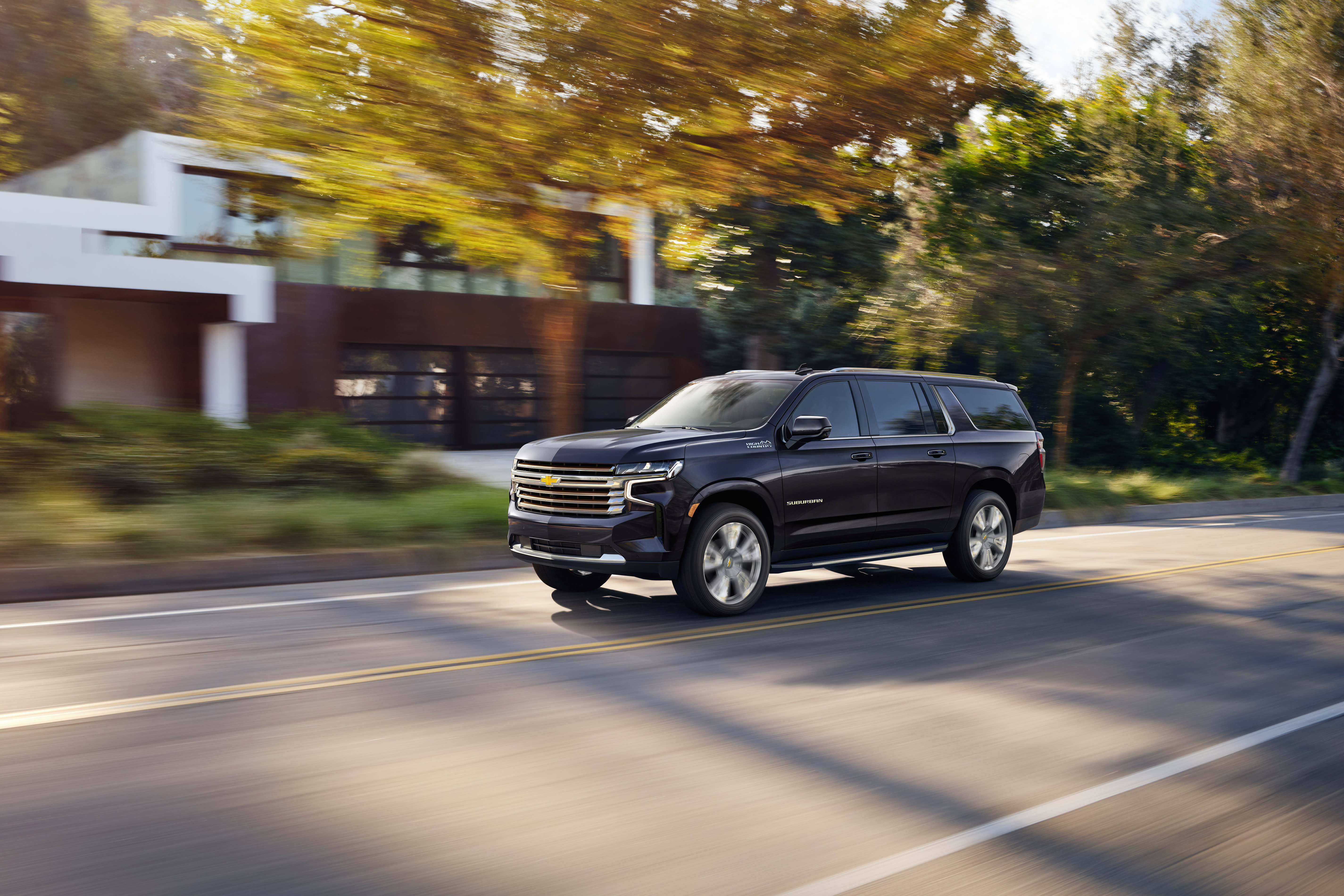 a dark 2022 Chevrolet Suburban driving down the road in Suburbia, USA.