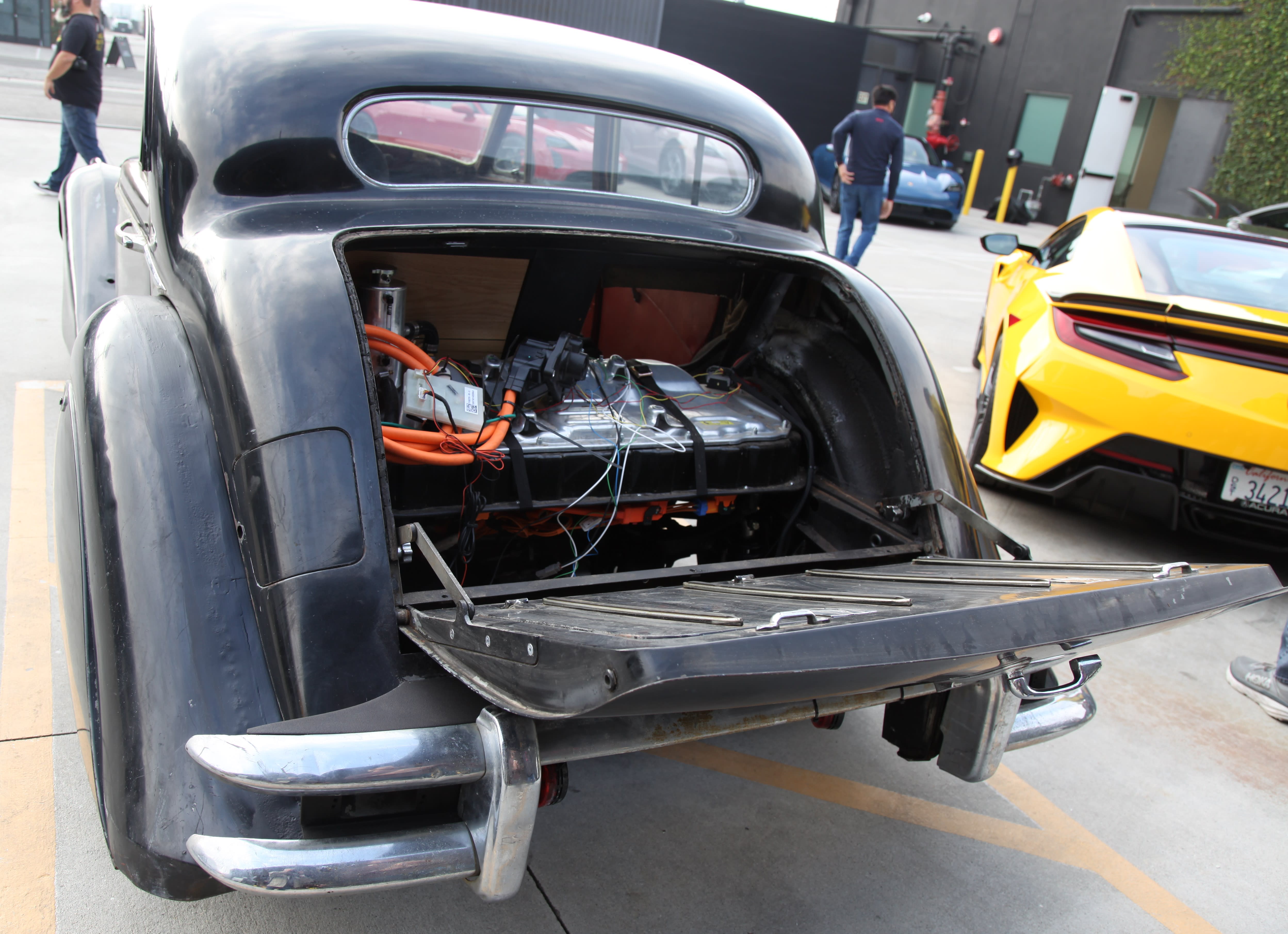 a classic hotrod with the trunk open, exposing the retrofitted electric engine