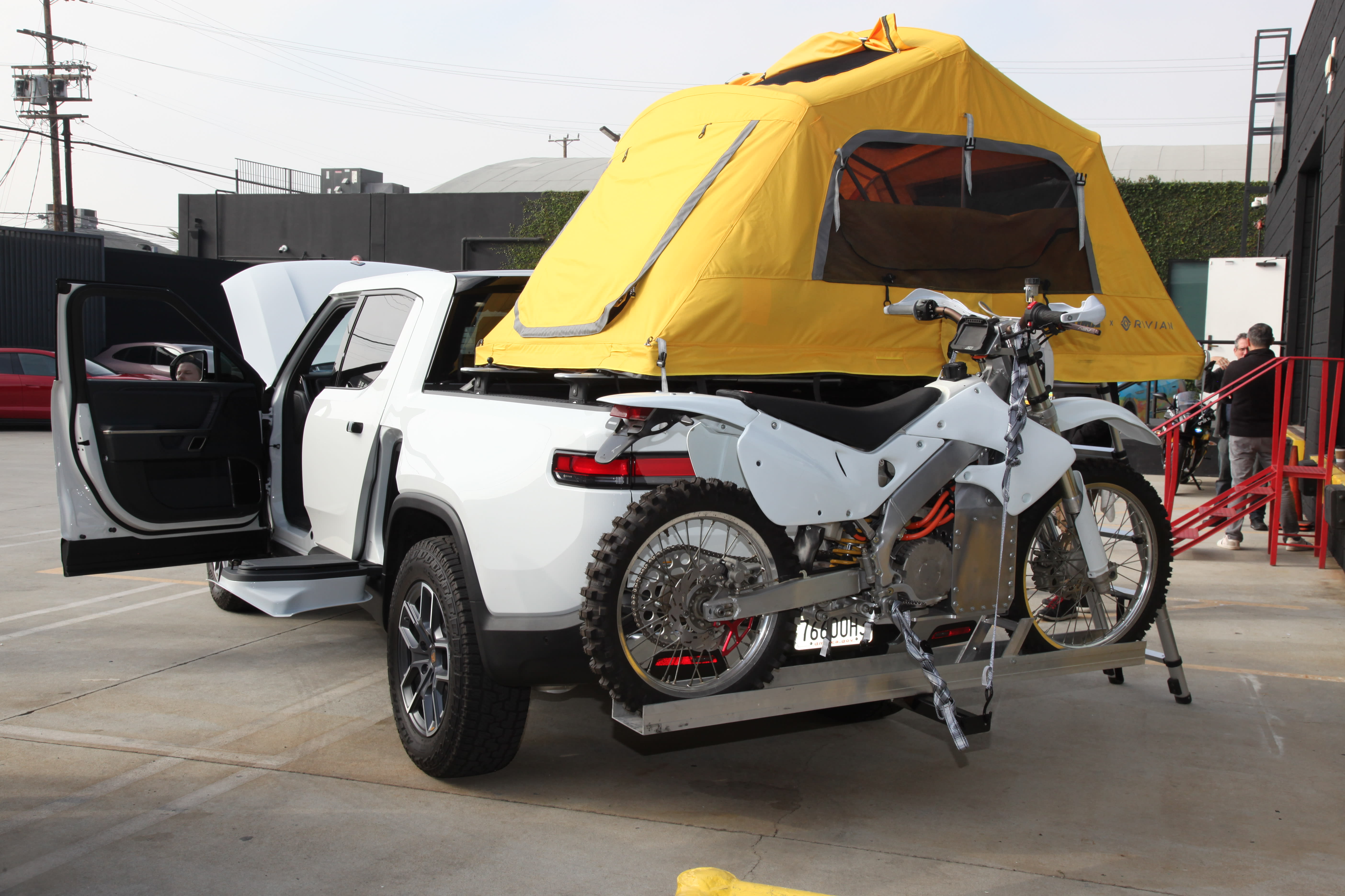 a tent perched up on the back of a Rivian pickup.