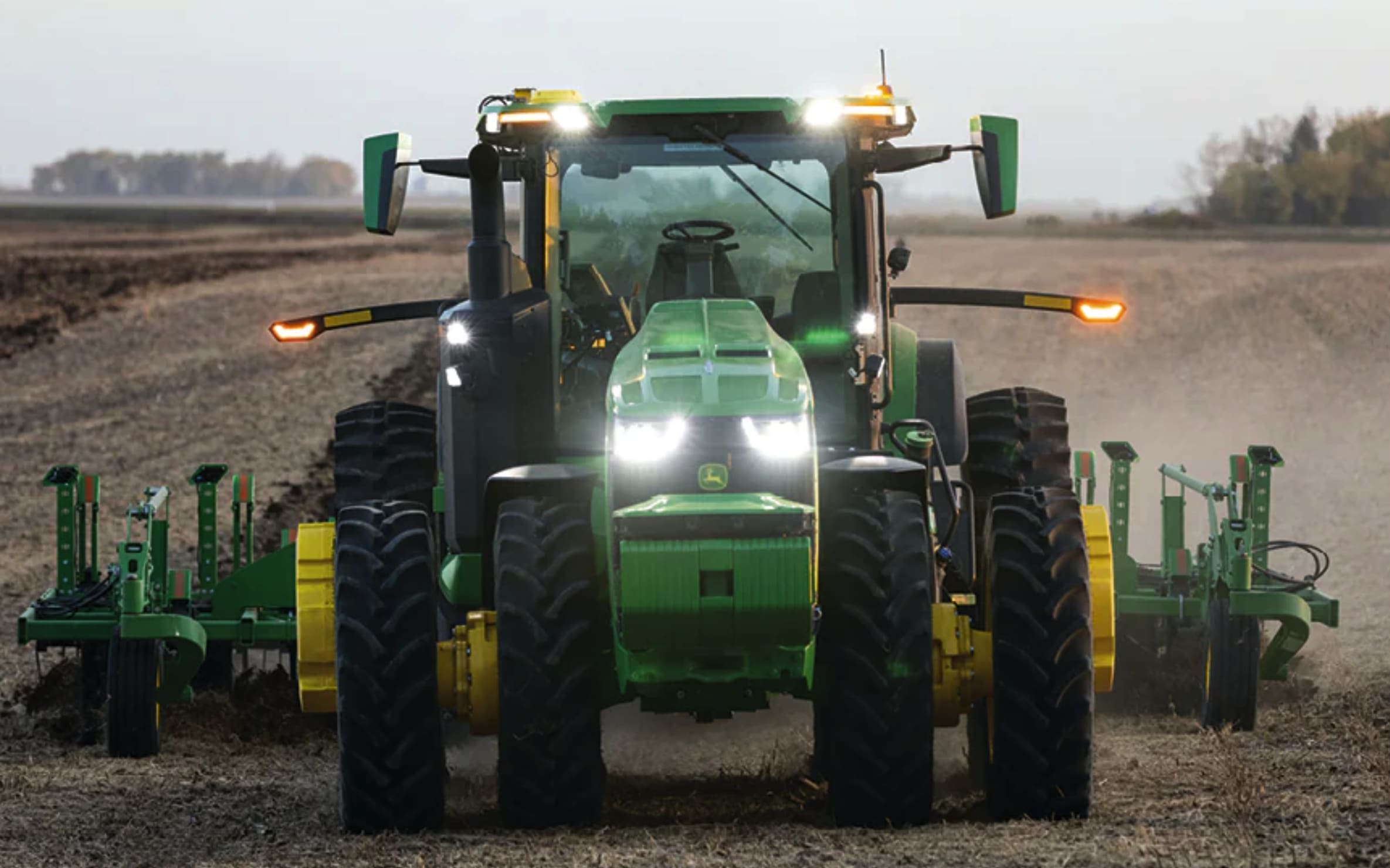 A green autonomous Deere tractor on a field.