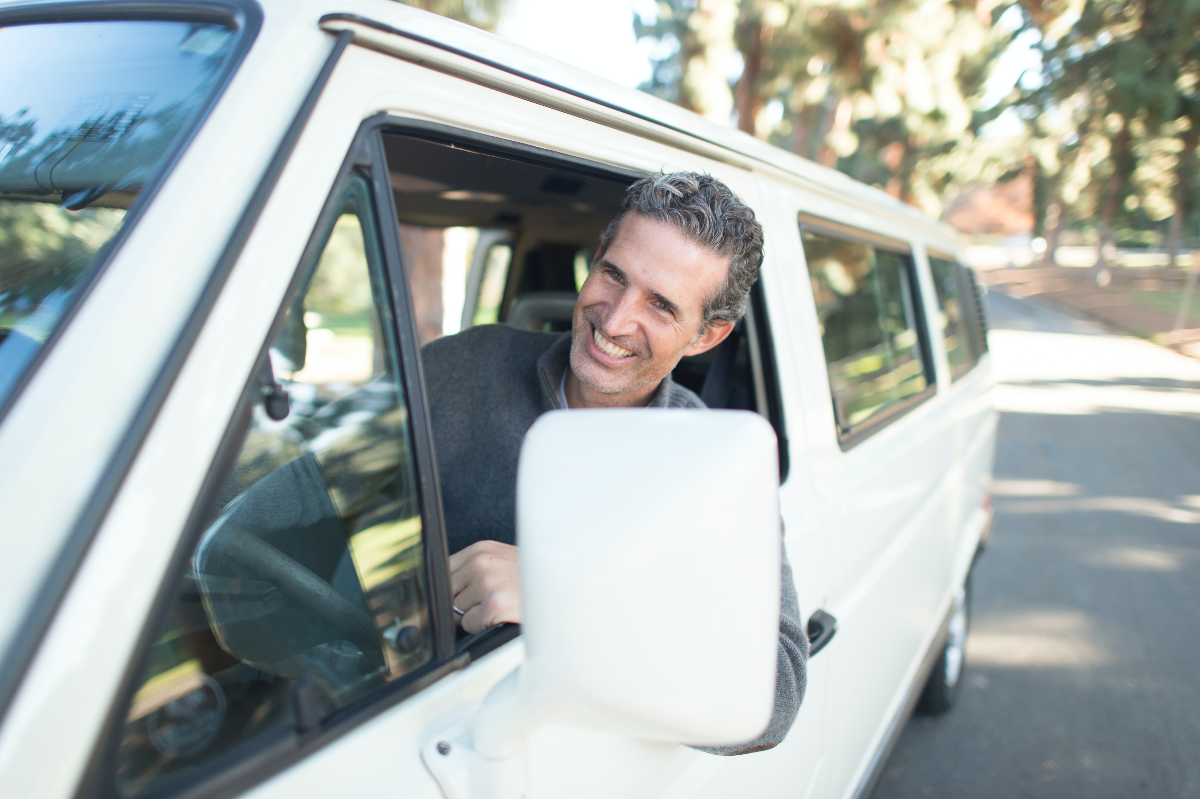 person sticking his head out the window of a large white SUV