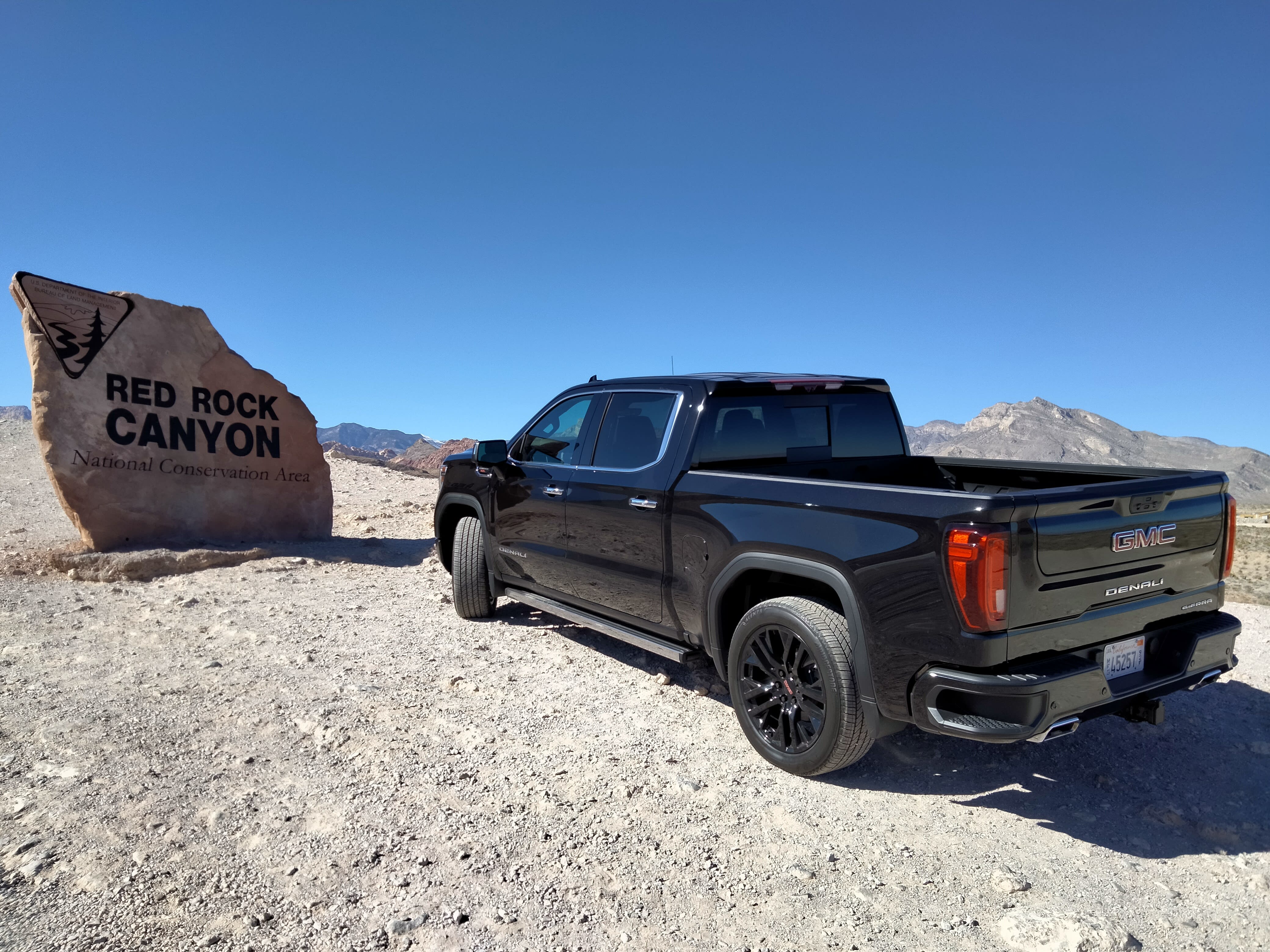 rear and side of the 2022 GMC Sierra Denali, with the sign for Red Rock Canyon in the background.