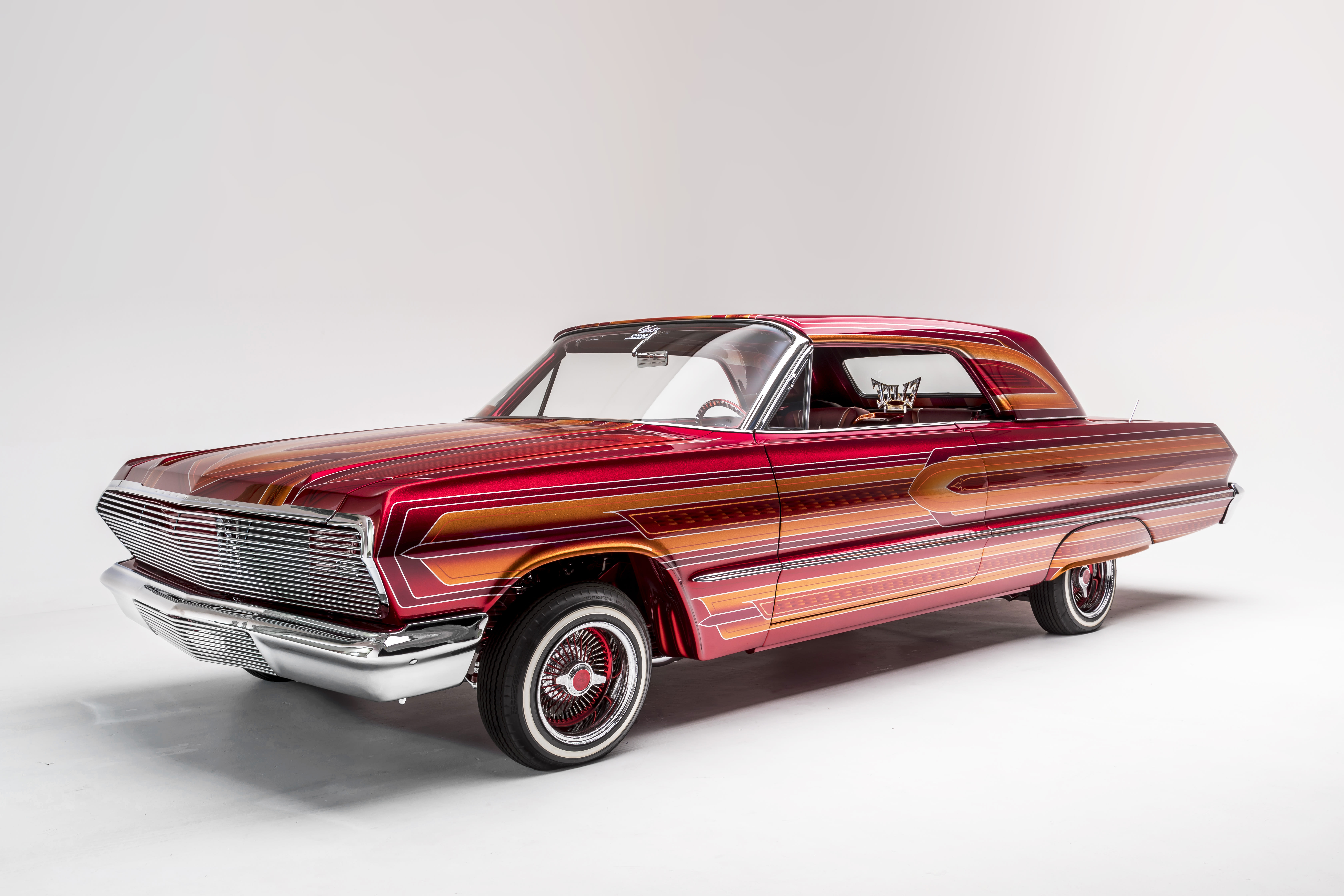 a dark pink with multiple stripes Chevrolet 1963 Impala, named El Rey