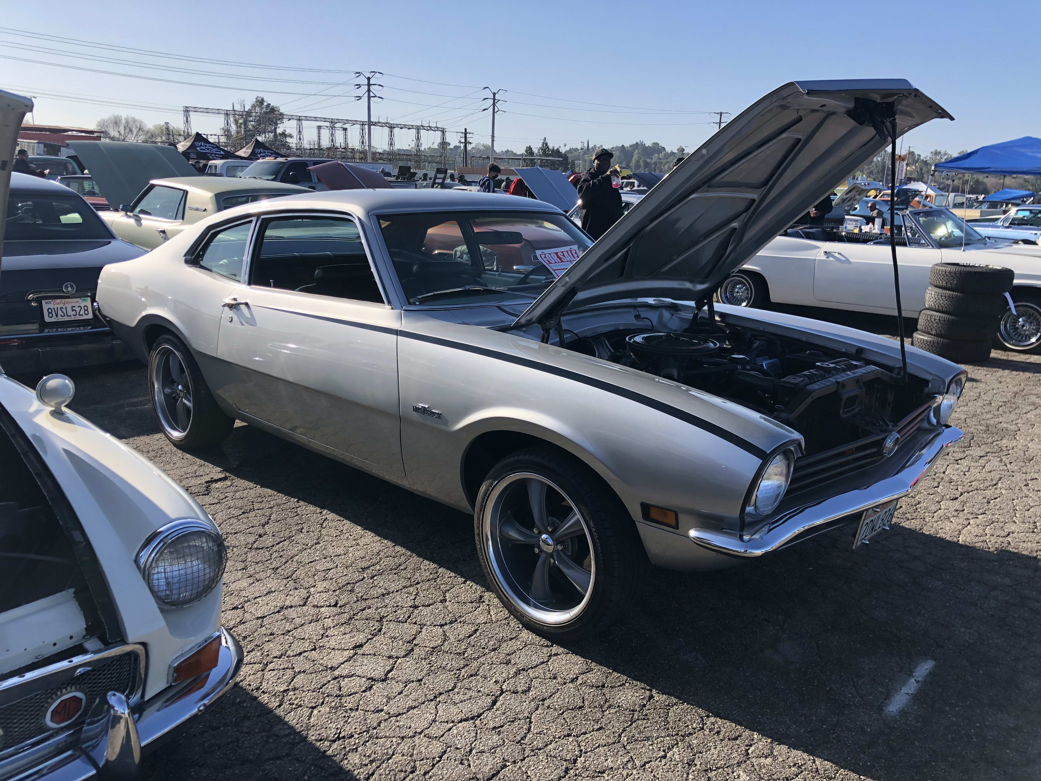 a gray Ford Mustang with the hood open, on display at the Pomona Auto Swap Meet