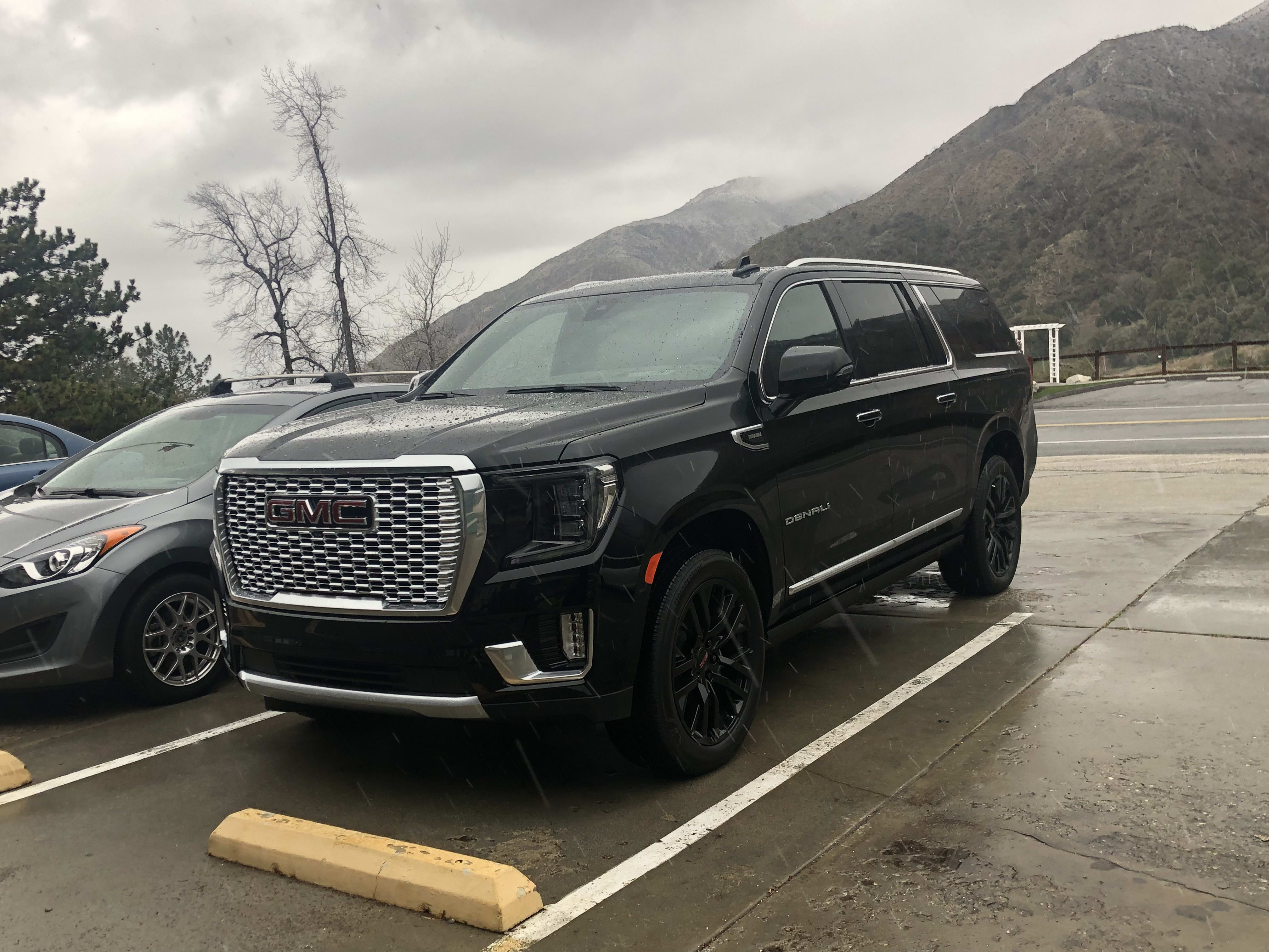 a black GMC Yukon XL Denali parked in a rather small parking spot.