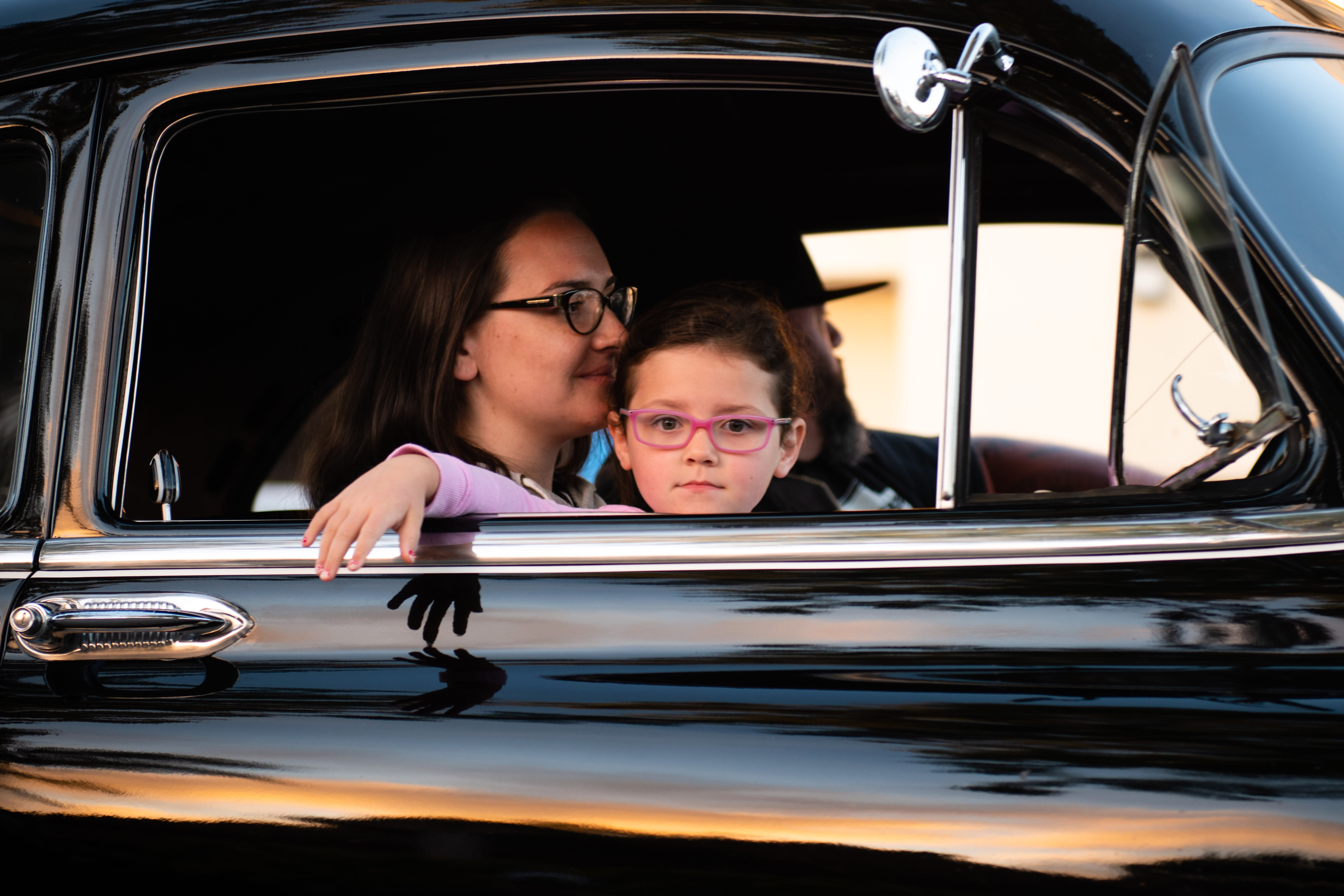 young child looking out the passenger window of a classic black family car