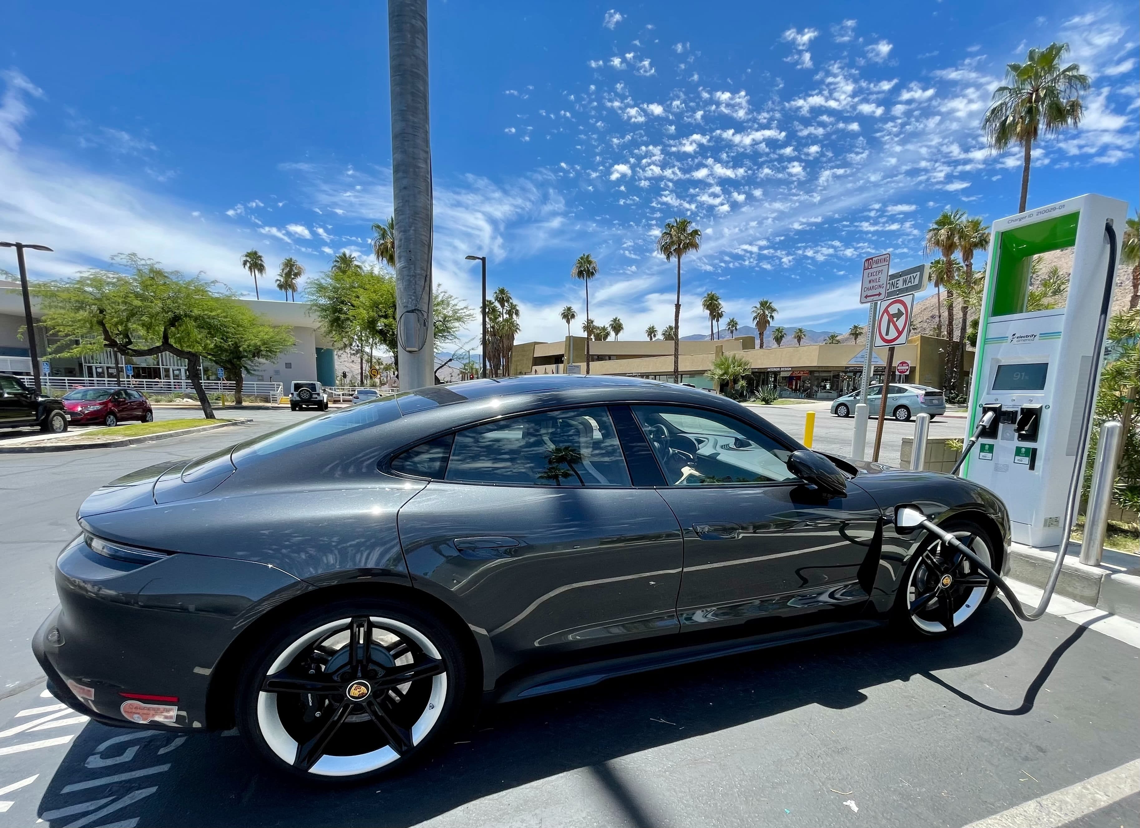 gray electric Porsche at a charging station in Palm Springs, California - palm trees in the background of course.