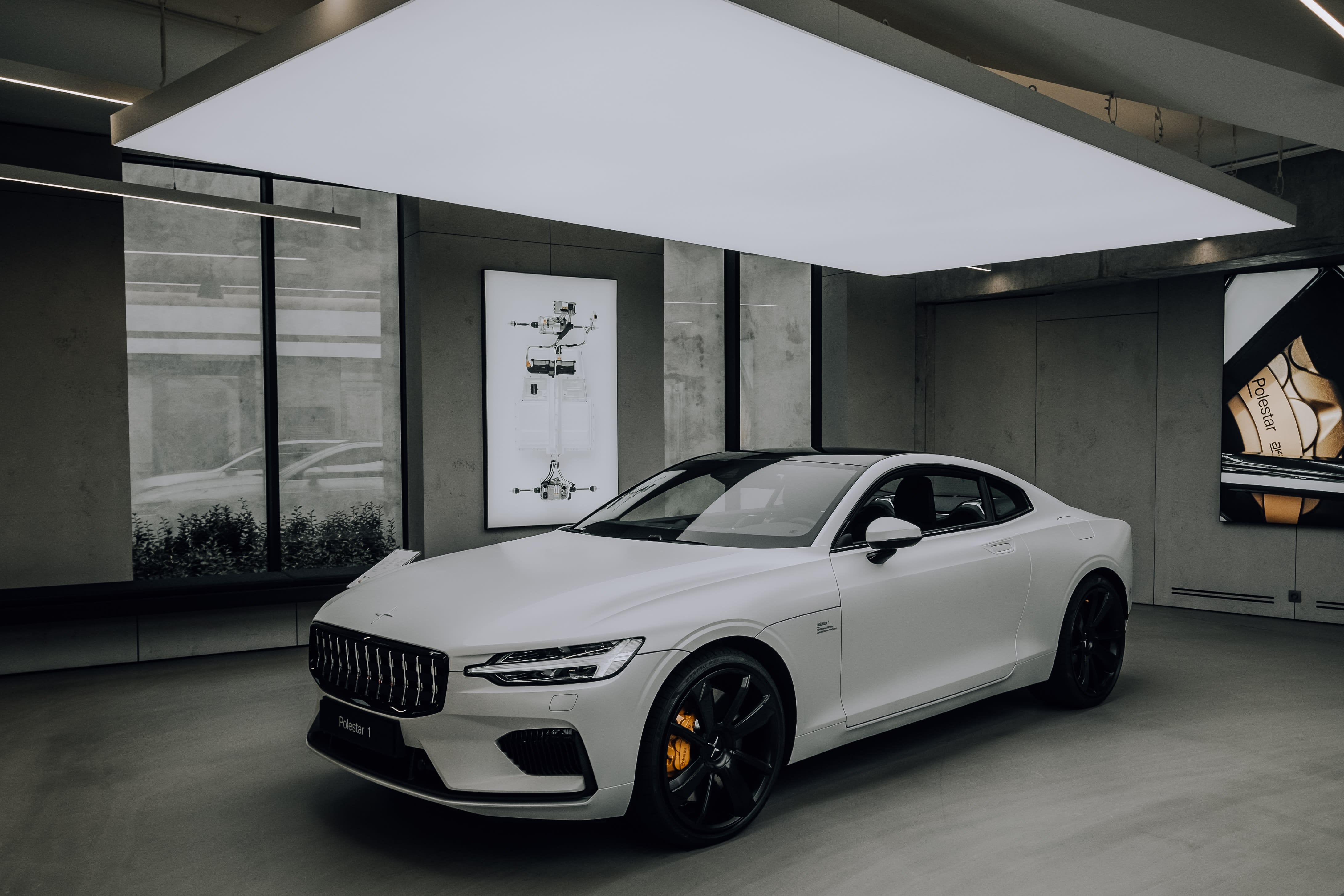 white Polestar electric vehicle standing in a very modern garage with gray cement walls.