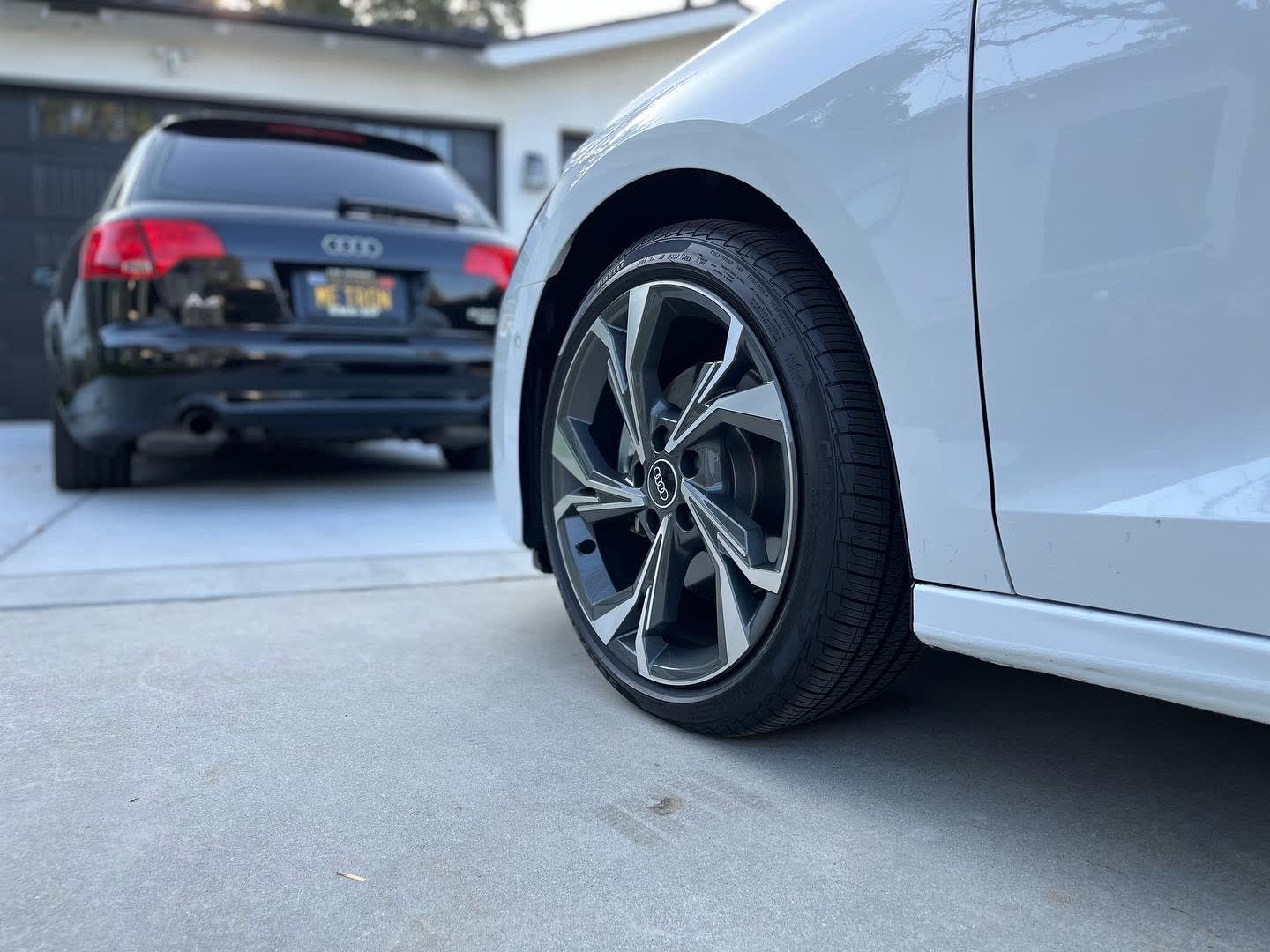 closeup of the wheel of the 2022 Audi A3, with an older Audi in the background.