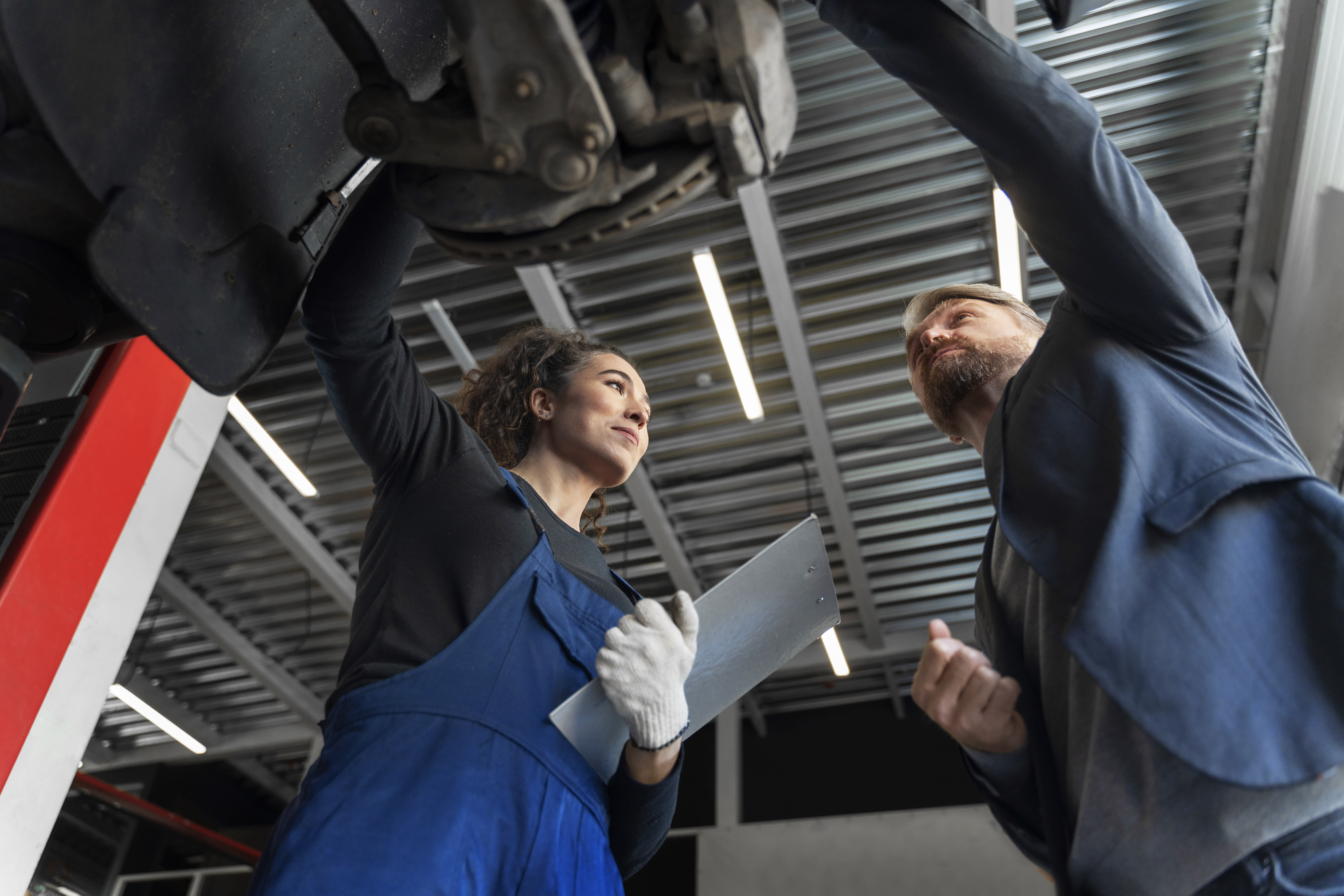 image of two mechanics talking by car