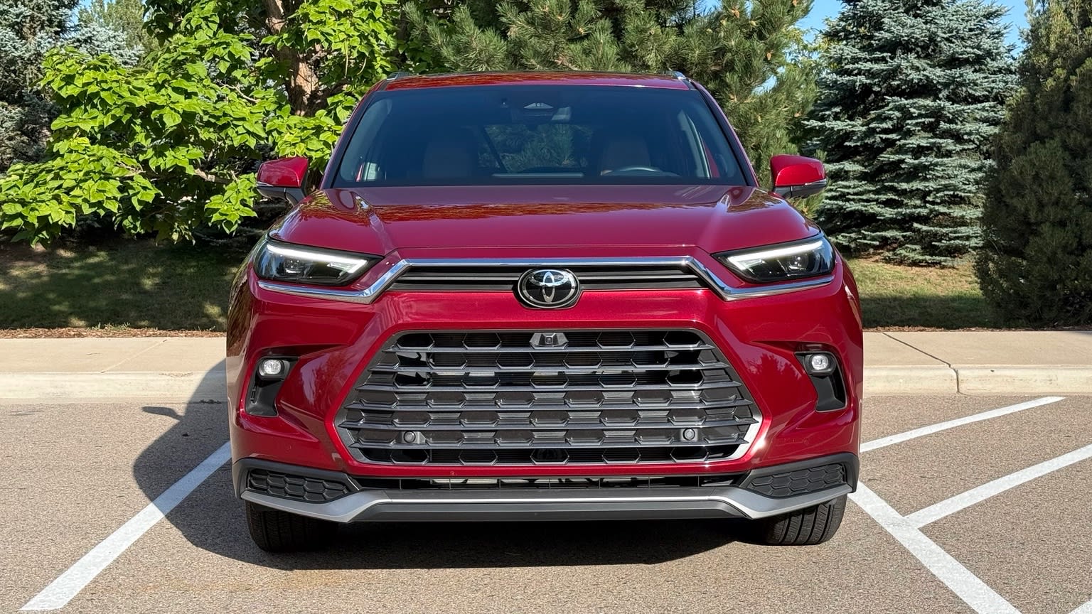Straight-on front view of the red 2026 Toyota Grand Highlander Hybrid MAX Platinum showing its grille and headlights.