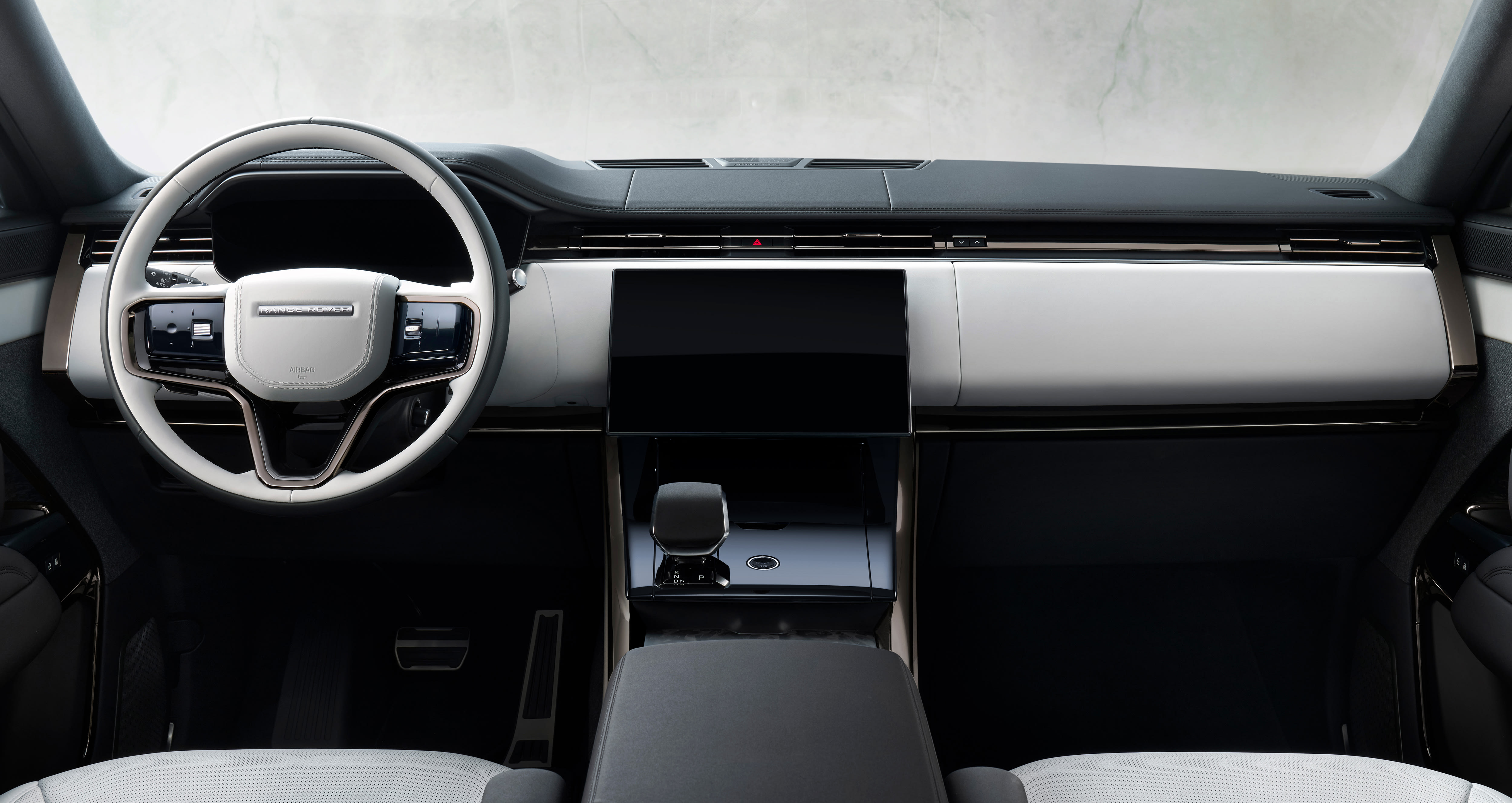 Range Rover Sport dashboard with a light-colored steering wheel, wide horizontal trim, and central touchscreen.