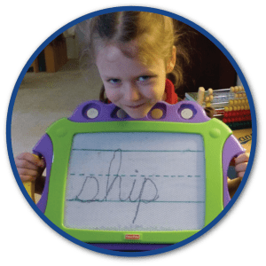 Left-handed Logic of English user proudly displaying her cursive handwriting on a reusable magnetic board.