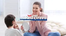 A woman showing a student how to pronounce a sound by pointing to the corners of her mouth.