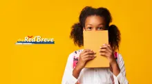 A girl smiling behind a yellow book