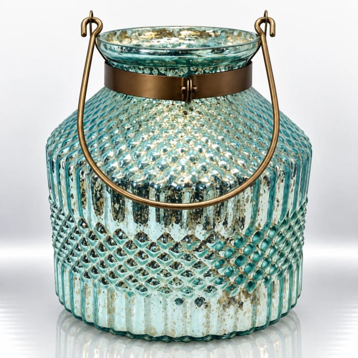 Aqua textured glass candle holder with antique gold speckles, raised diamond patterns, bronze neck band and curved metal handle.