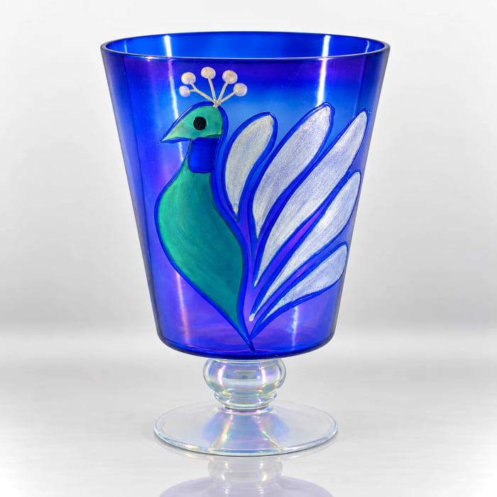 Blue glass pedestal candle holder featuring a colourful peacock design with silver feather detailing and an iridescent base.