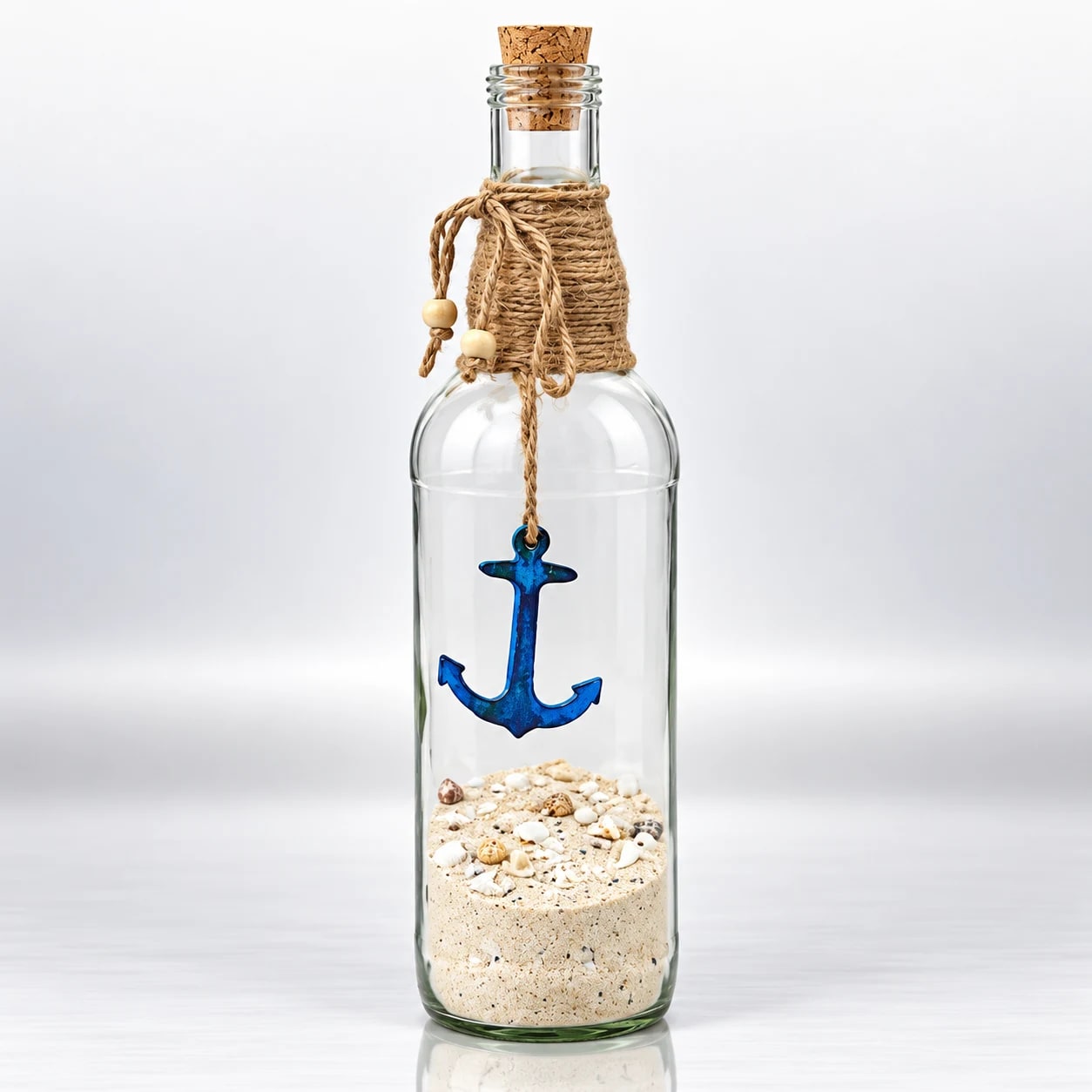 Clear glass bottle with blue anchor, sand, seashells, cork and jute rope