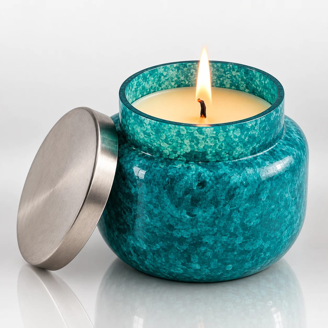 Teal textured metal candle jar with silver-toned lid and lit candle