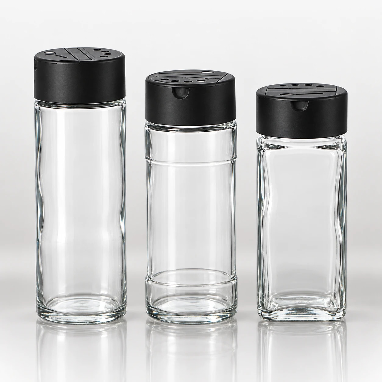 Clear glass spice jars with black shaker lids in assorted shapes