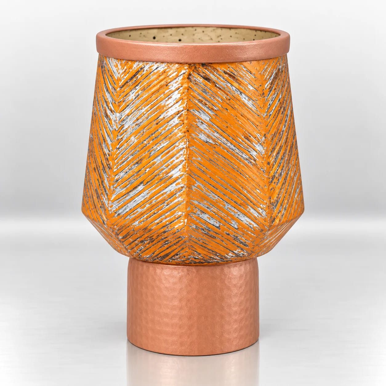Orange glass candle holder with a silver leaf-pattern design and copper-toned cylindrical base.