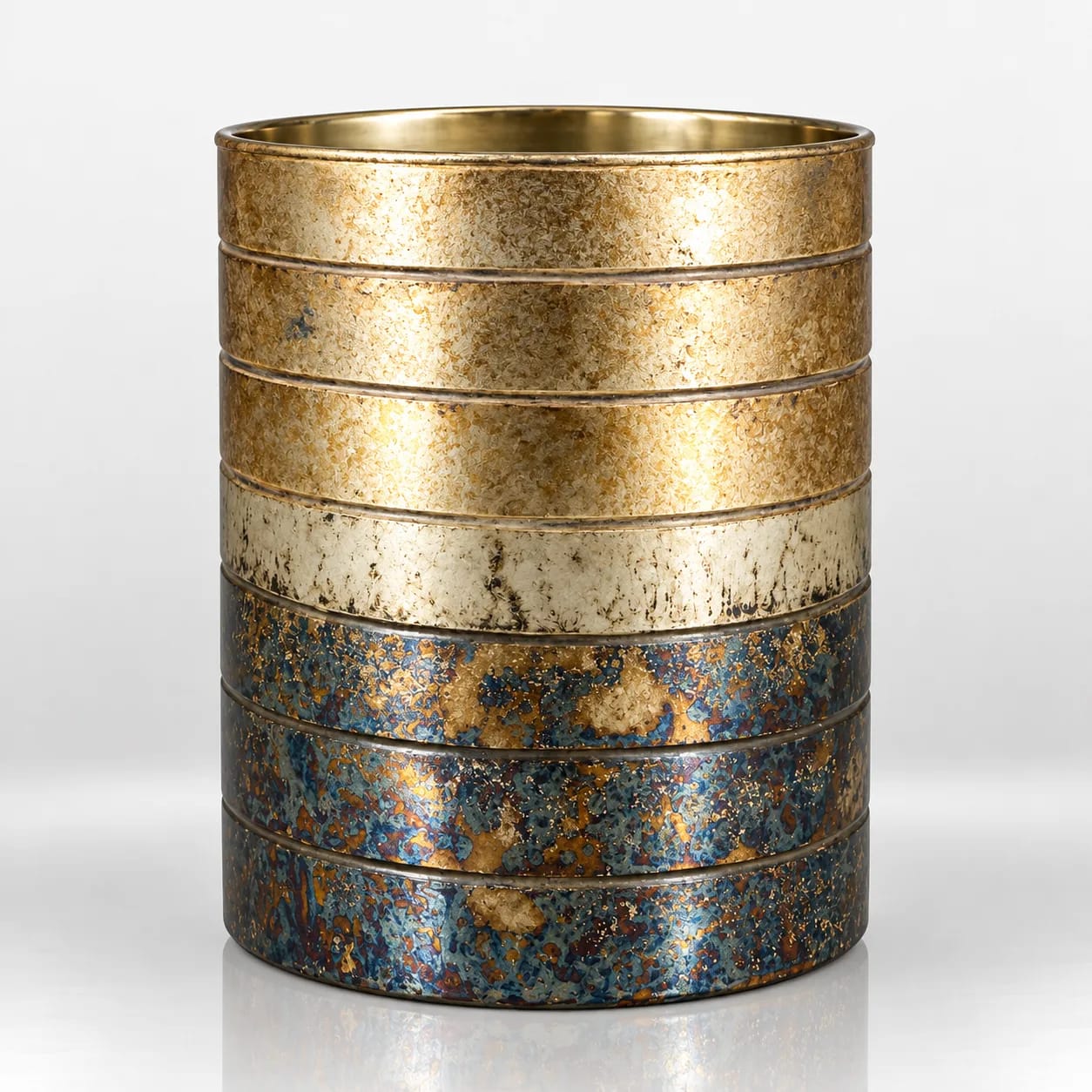 Cylindrical candle holder with layered gold, ivory and blue textured bands and an antique metallic finish.